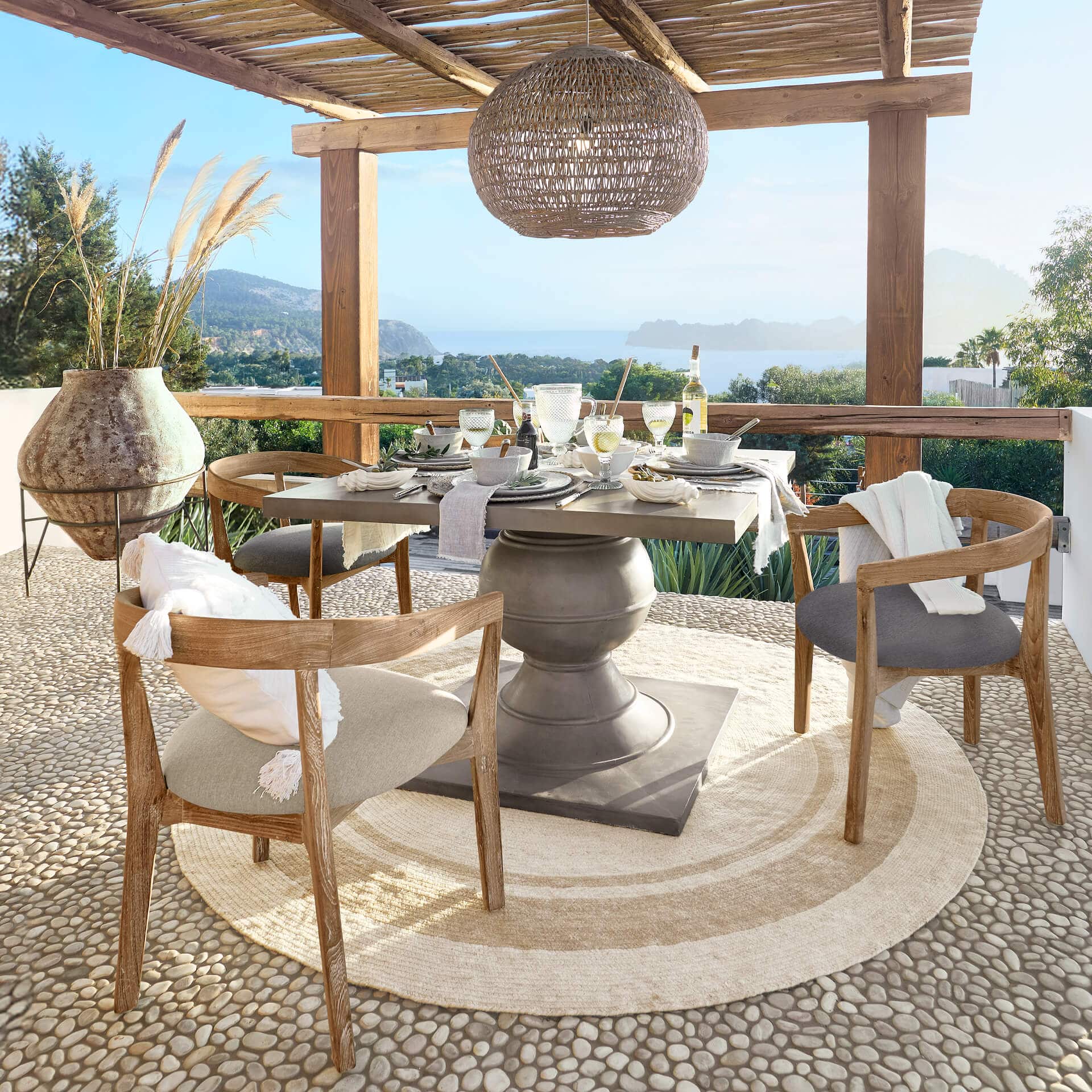 Gartentisch mit Betonsockel und Holzstühlen auf Terrasse mit Meerblick