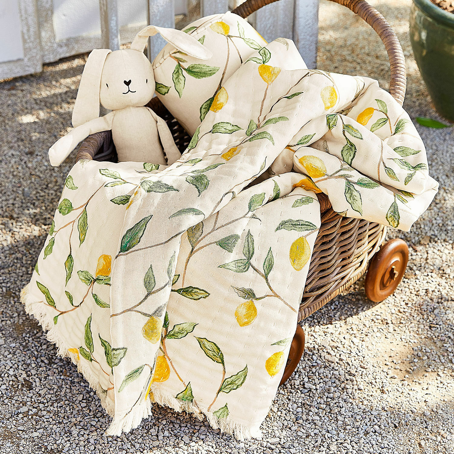Plaid Palerina Baumwoll-Decke in Creme mit gelben Zitronen und grünen Blättern im Korb aus Rattan