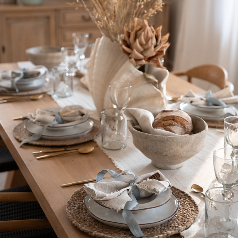 Rustikaler Holztisch mit Keramiktellern, Leinenservietten und getrockneten Blumen als Tischdeko