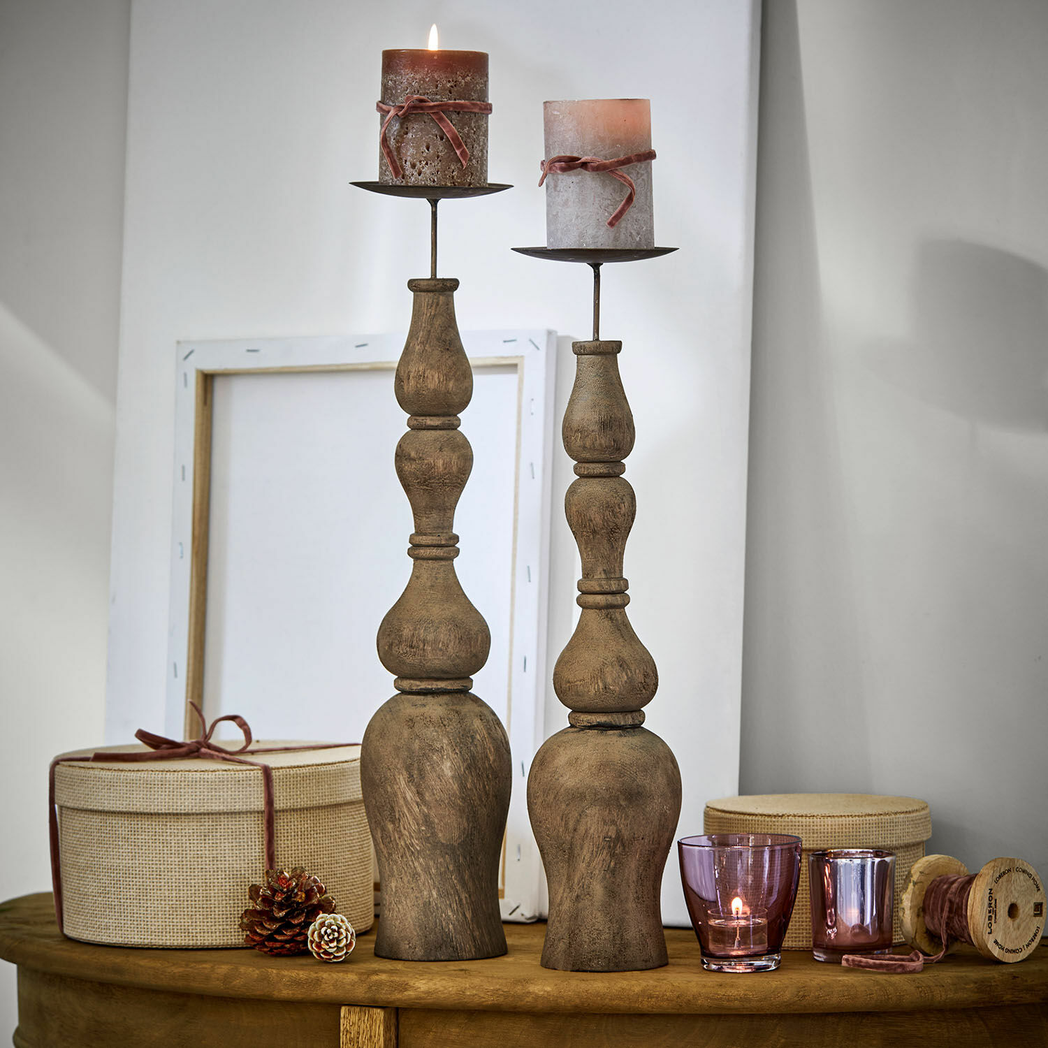 Kerzenständer 2er Set Fleuries-sur-Marne Zwei rustikale Kerzenhalter aus Holz mit braunen Kerzen und dekorativen Boxen auf Holztisch
