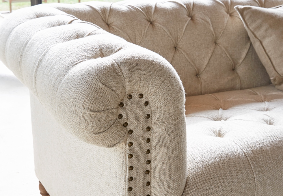 Beige klassisches Sofa aus Stoff mit gesteppter Rückenlehne und dekorativen Nägeln im Wohnzimmer