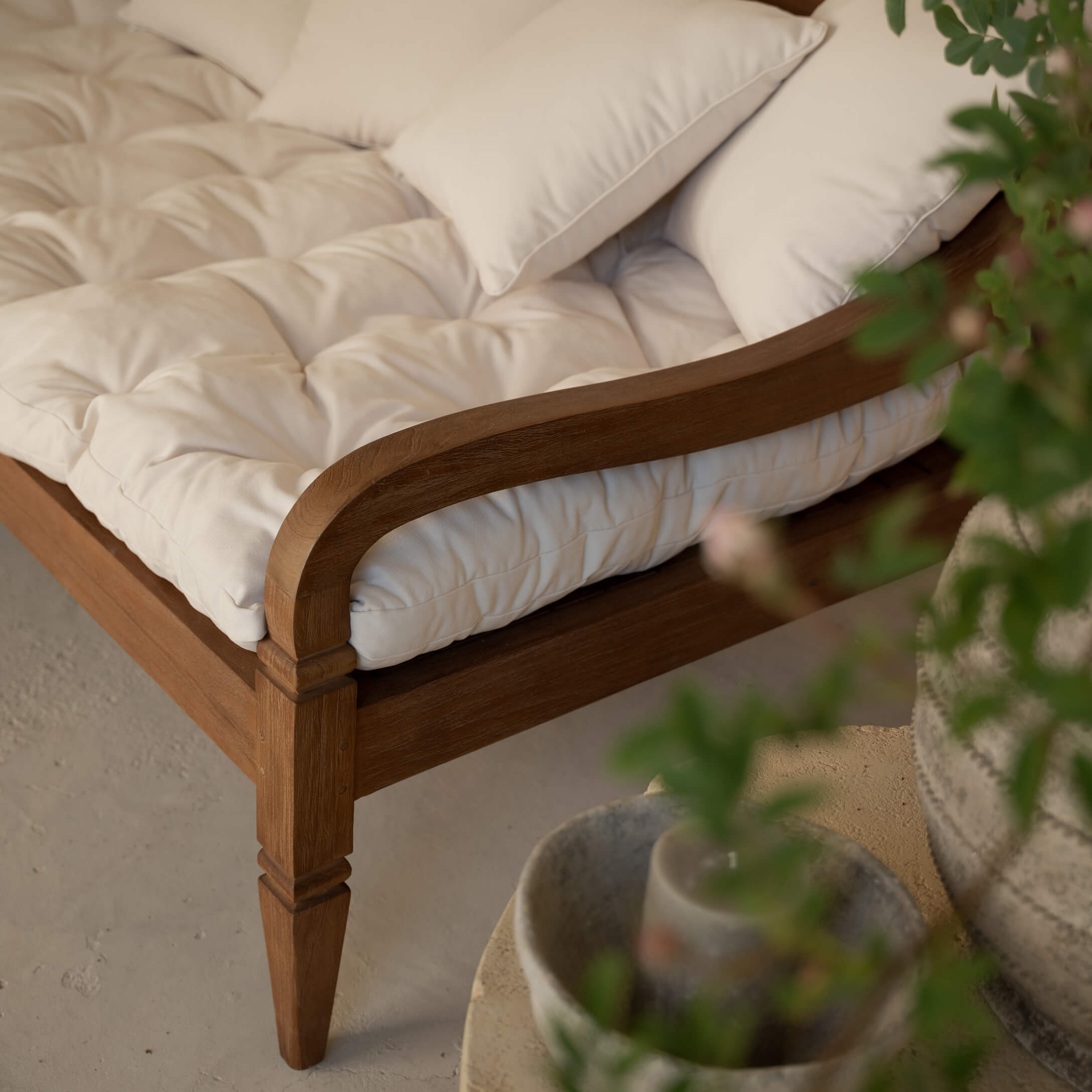 Holzrahmen eines Sofas mit cremefarbenem, gesteppter Polsterung und weichen Dekokissen