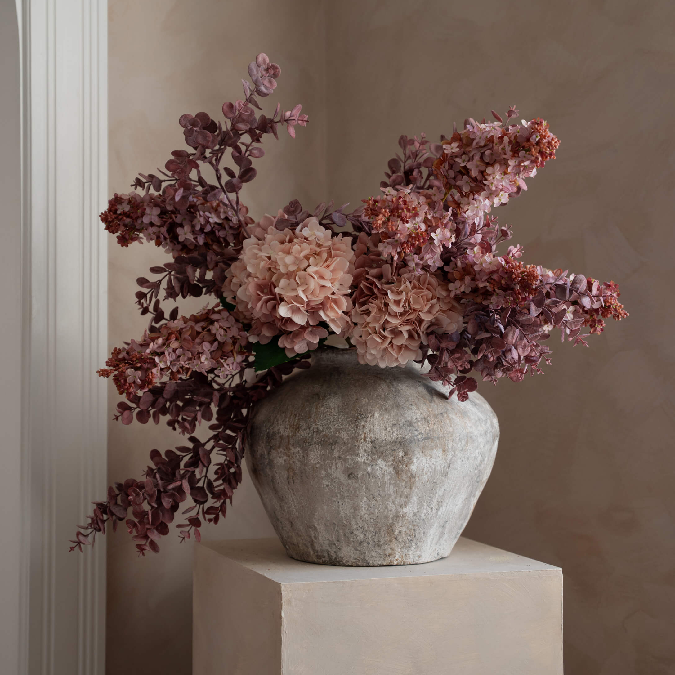 Dekorativer grauer Steinvase mit rosa und violetten künstlichen Blumen für Innenräume
