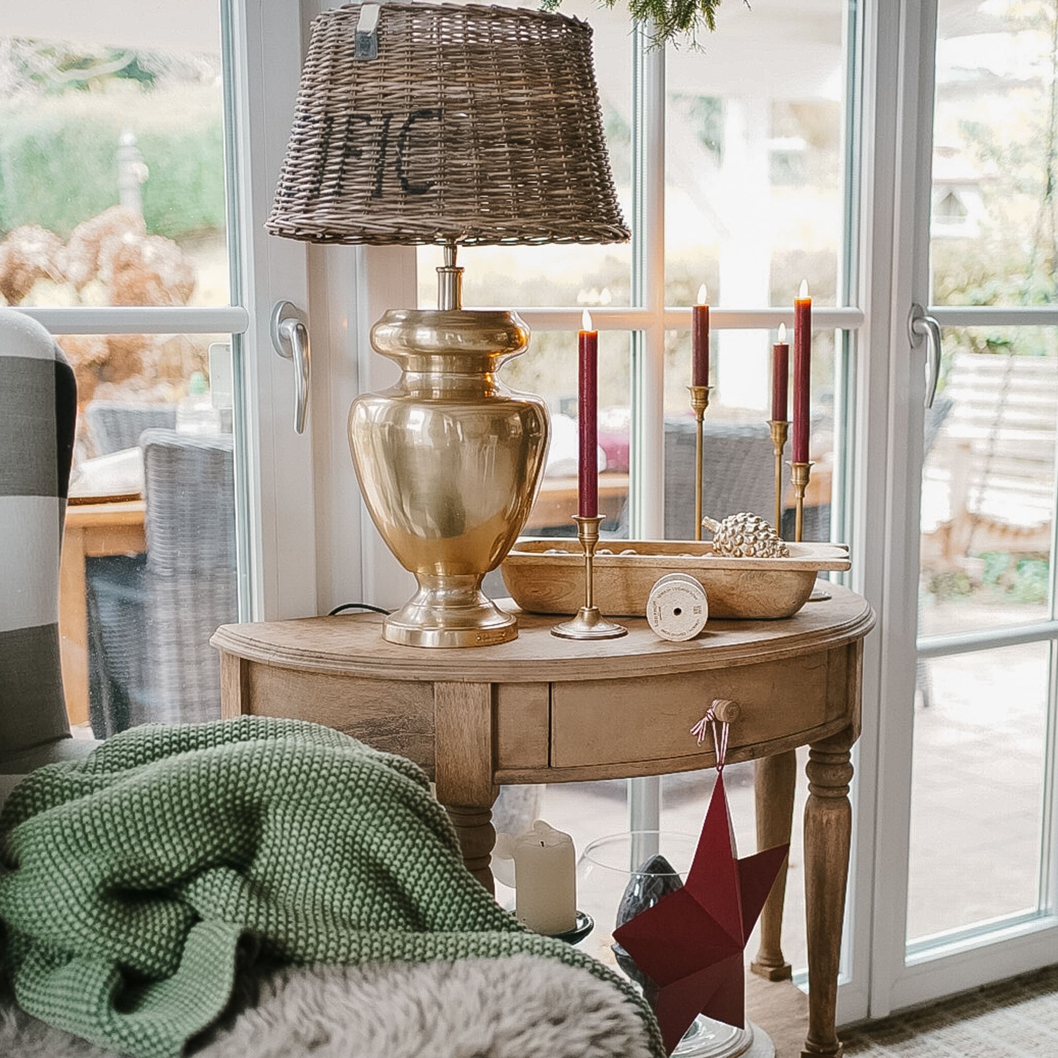 Holztisch mit messingfarbener Lampe und roten Kerzen, weihnachtliche Dekoration im Wohnzimmer