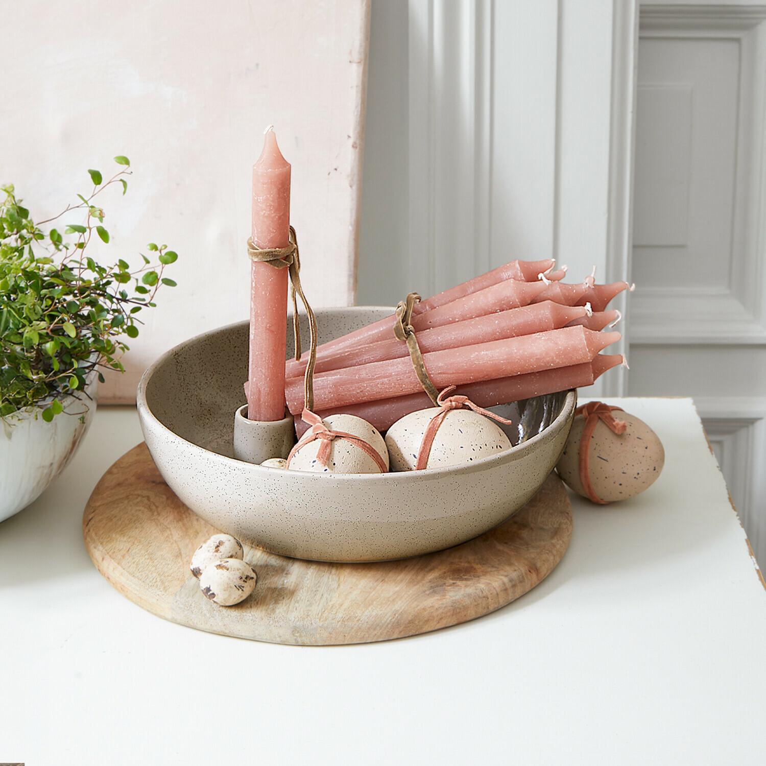 Set aus rosa Kerzen und beigen Keramikdekorationen in Schale auf Holzunterlage