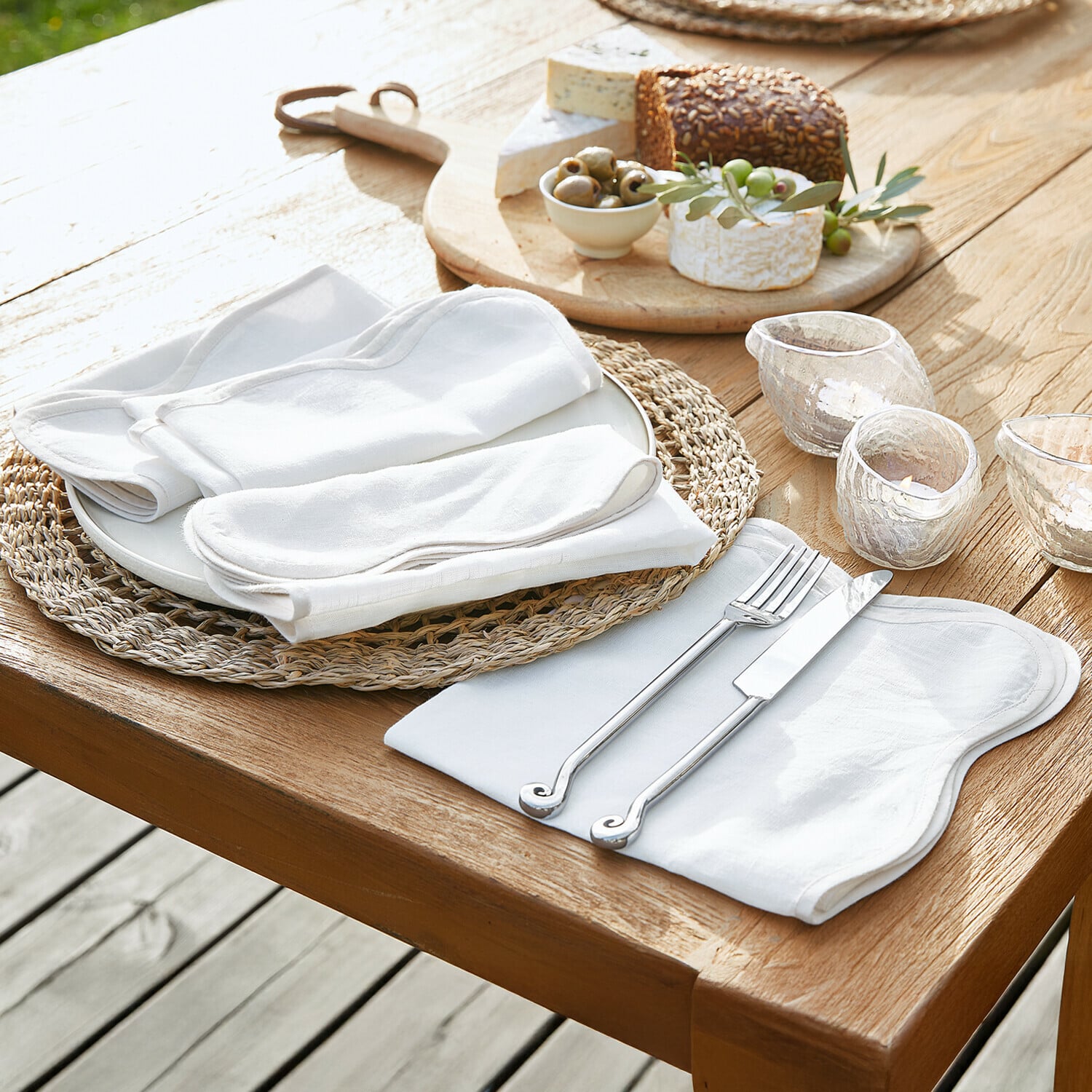 Serviette 4er Set Aelvra Set aus weißen Leinenservietten und Tischdecken auf Holztisch mit Messer und Gabel
