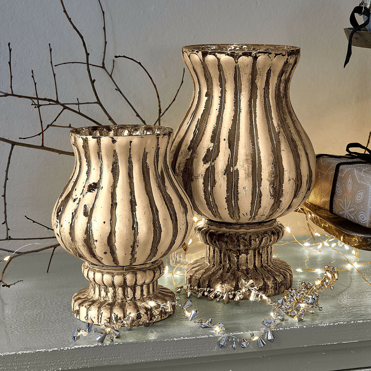 Zwei dekorative Kerzenhalter aus Metall in antikgold mit geriffeltem Design und festlicher Lichterkette
