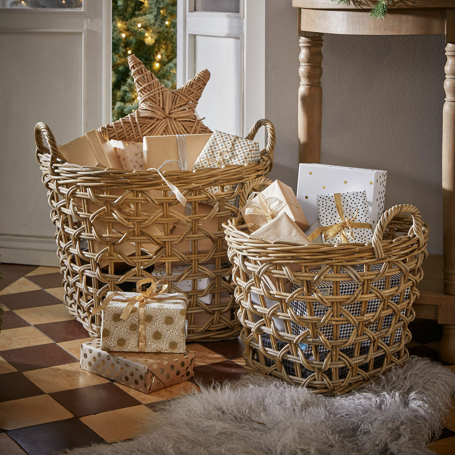 Zwei naturfarbene Rattankörbe mit Geschenken und Weihnachtsdeko auf gefliestem Boden.