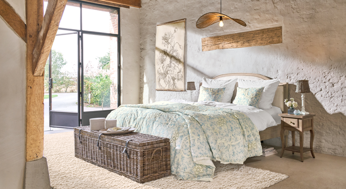 Gemütliches Schlafzimmer mit Holzbett und heller Bettwäsche mit floralem Muster, natürliche Materialien und Dekorationen