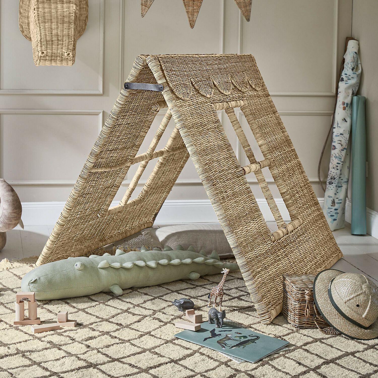 Kinderzelt aus natürlichem Rattan auf Teppich mit Holzspielzeug und Safari-Hut