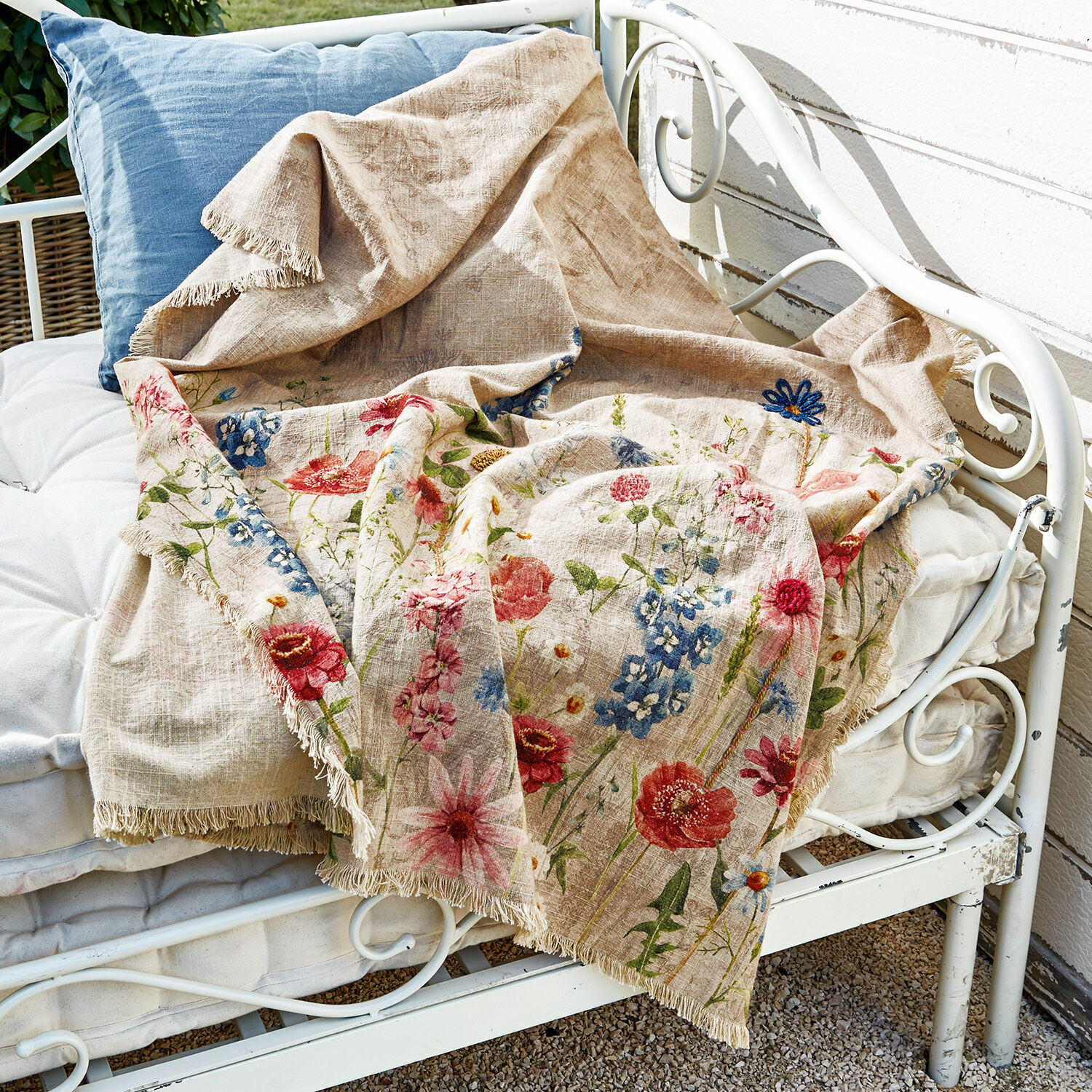 Plaid Eleonoire Beige Leinen-Decke mit buntem Blumenmuster und Fransen auf weißer Metallbank