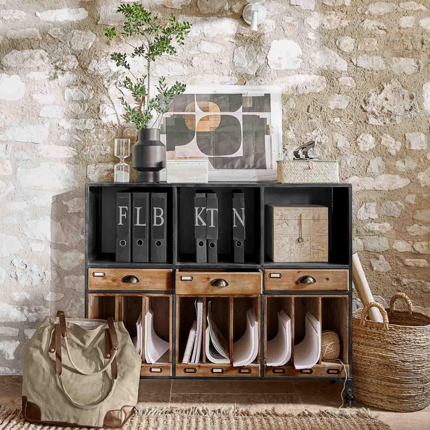 Schwarzer Metall-Holz-Schrank mit Schubladen und Ordnern vor rustikaler Steinwand im Loft-Stil