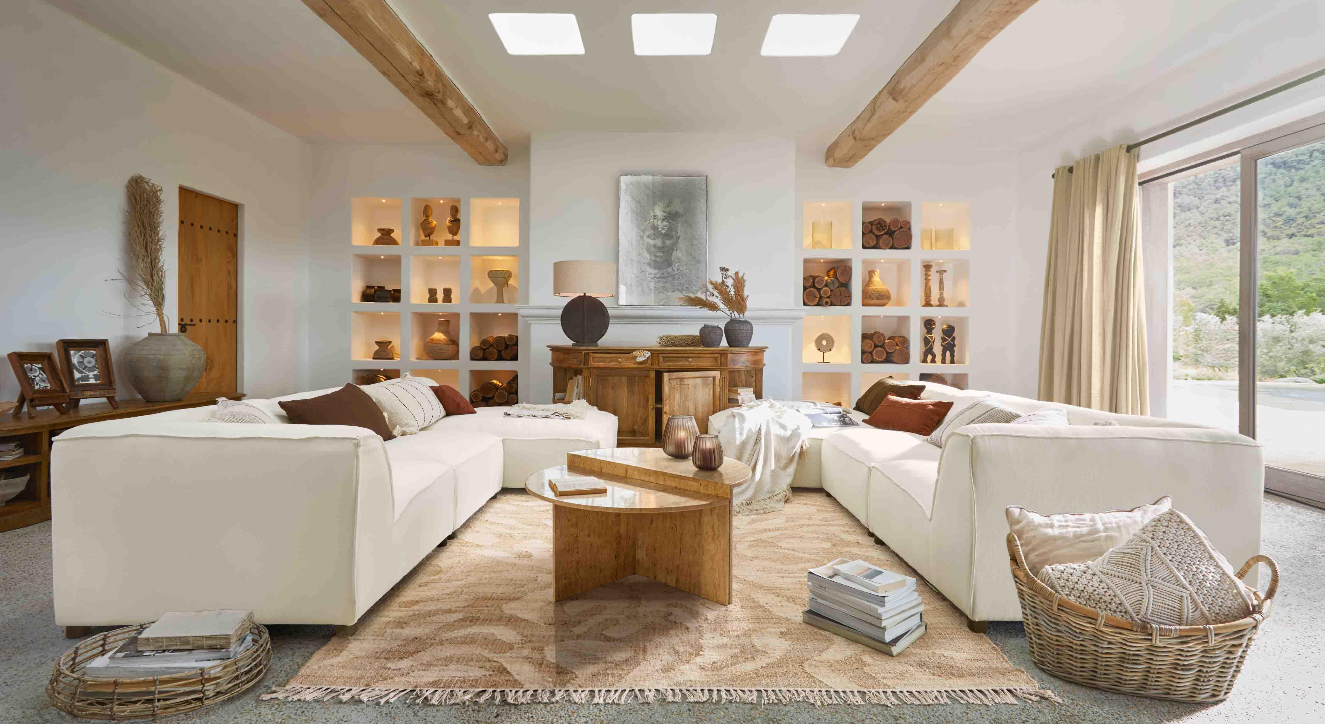 Geräumiges Wohnzimmer mit weißem Modulsofa, Holztisch und Dekorationen in Naturtönen