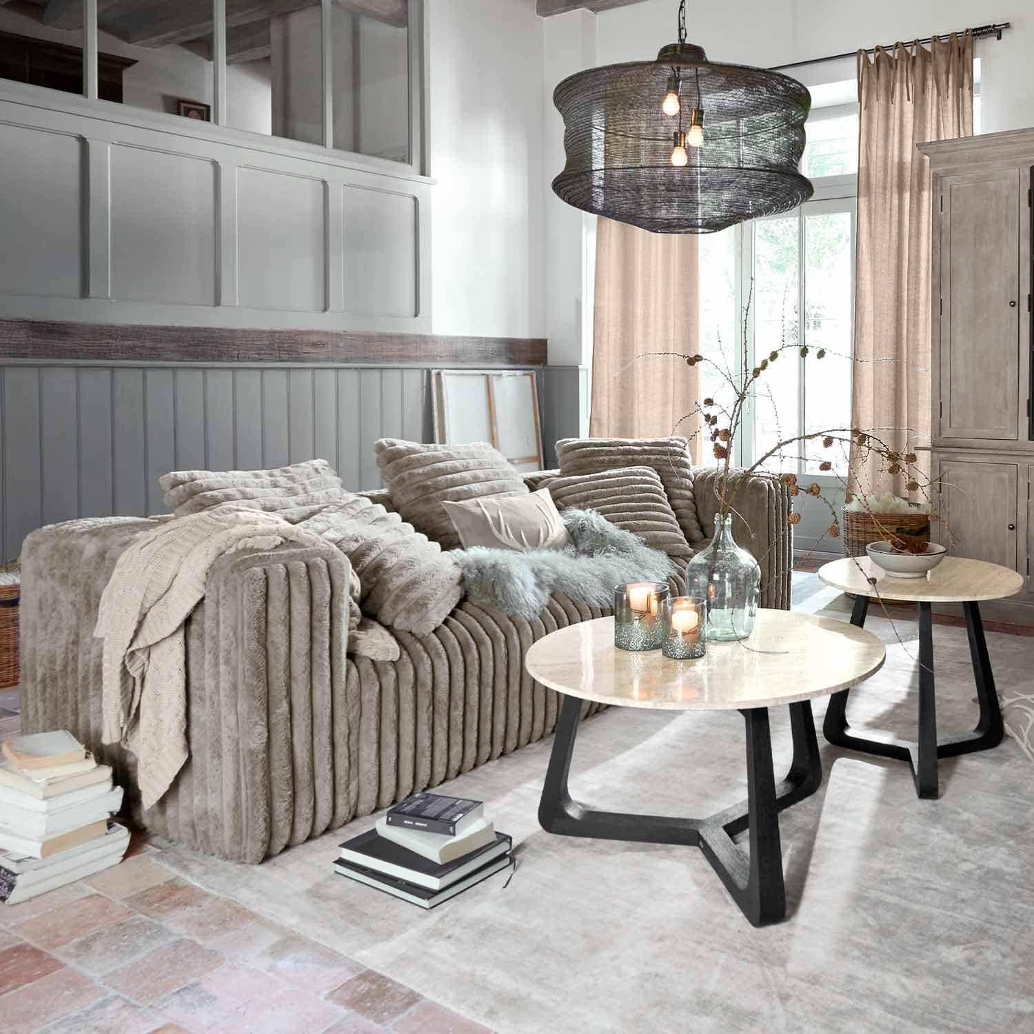 Beige Sofa aus weichem Stoff in modernem Wohnzimmer mit zwei runden Couchtischen aus Holz und Metall