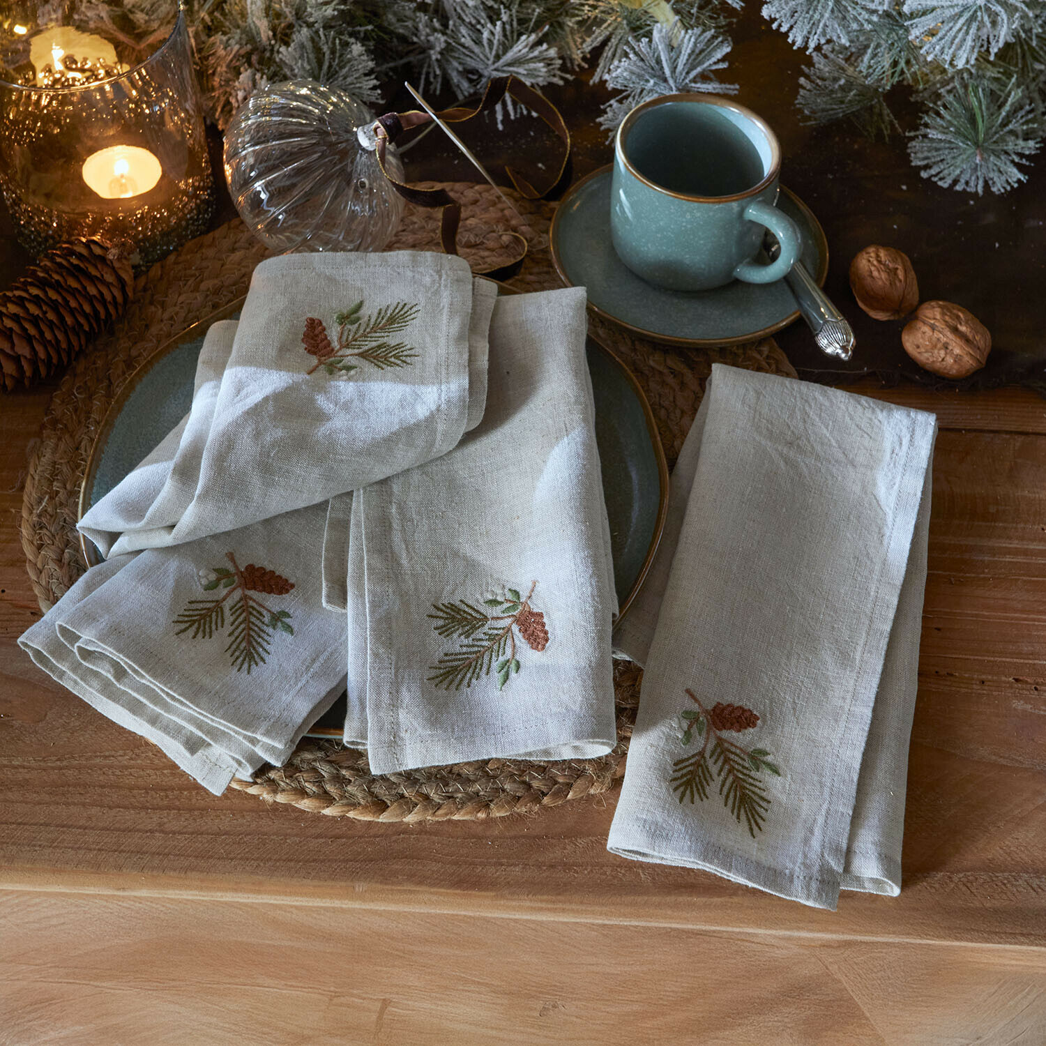 Serviette 4er Set Arlida Leinenservietten mit Kiefernzapfen-Stickerei auf rustikalem Tisch mit Weihnachtsdeko