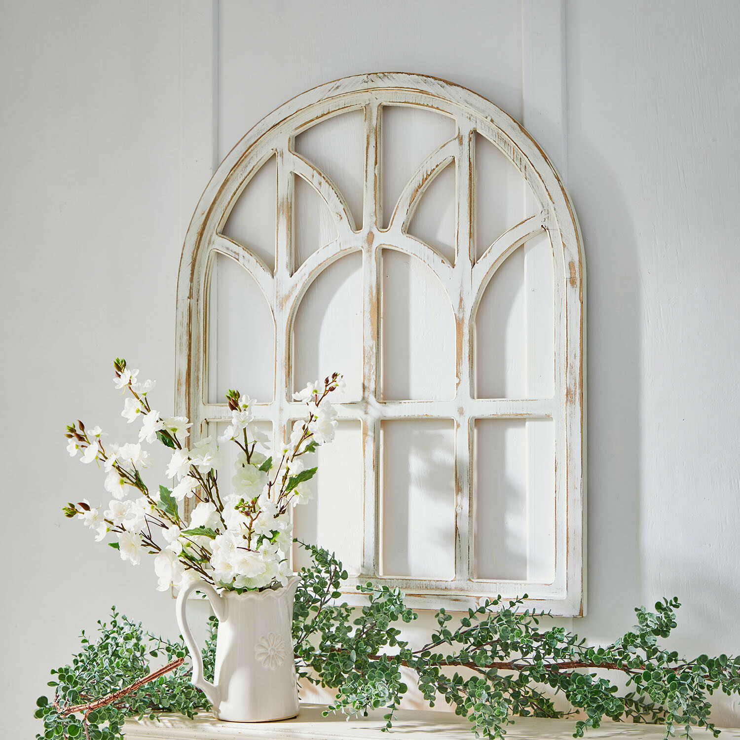Weißes, antik wirkendes Holz-Wandpaneel mit weißen Blumen in Keramikvase dekorativ arrangiert