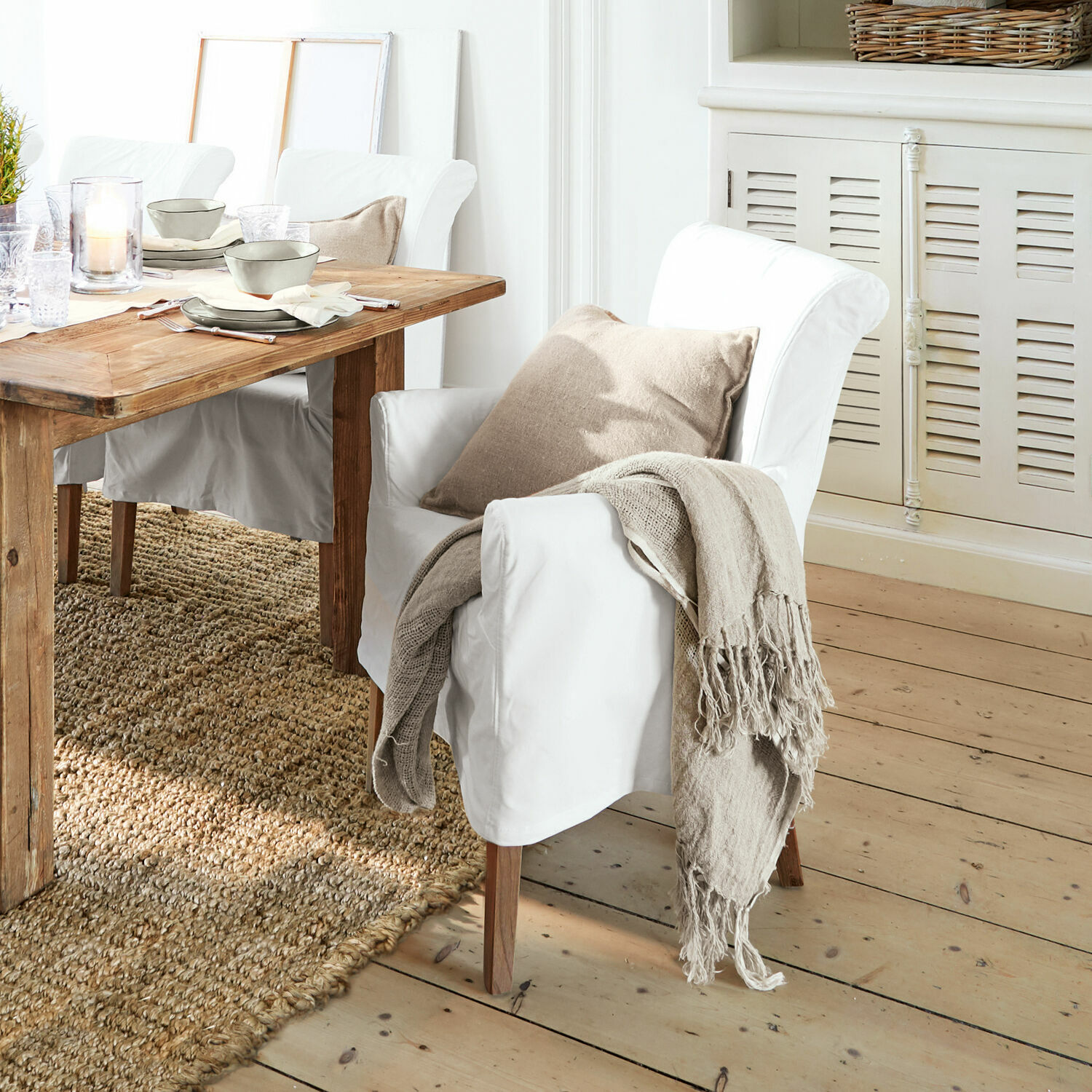 Stuhl Amherst Weißer Sessel mit Holzbeinen, beigem Kissen und naturfarbenem Plaid im Esszimmer mit Holztisch