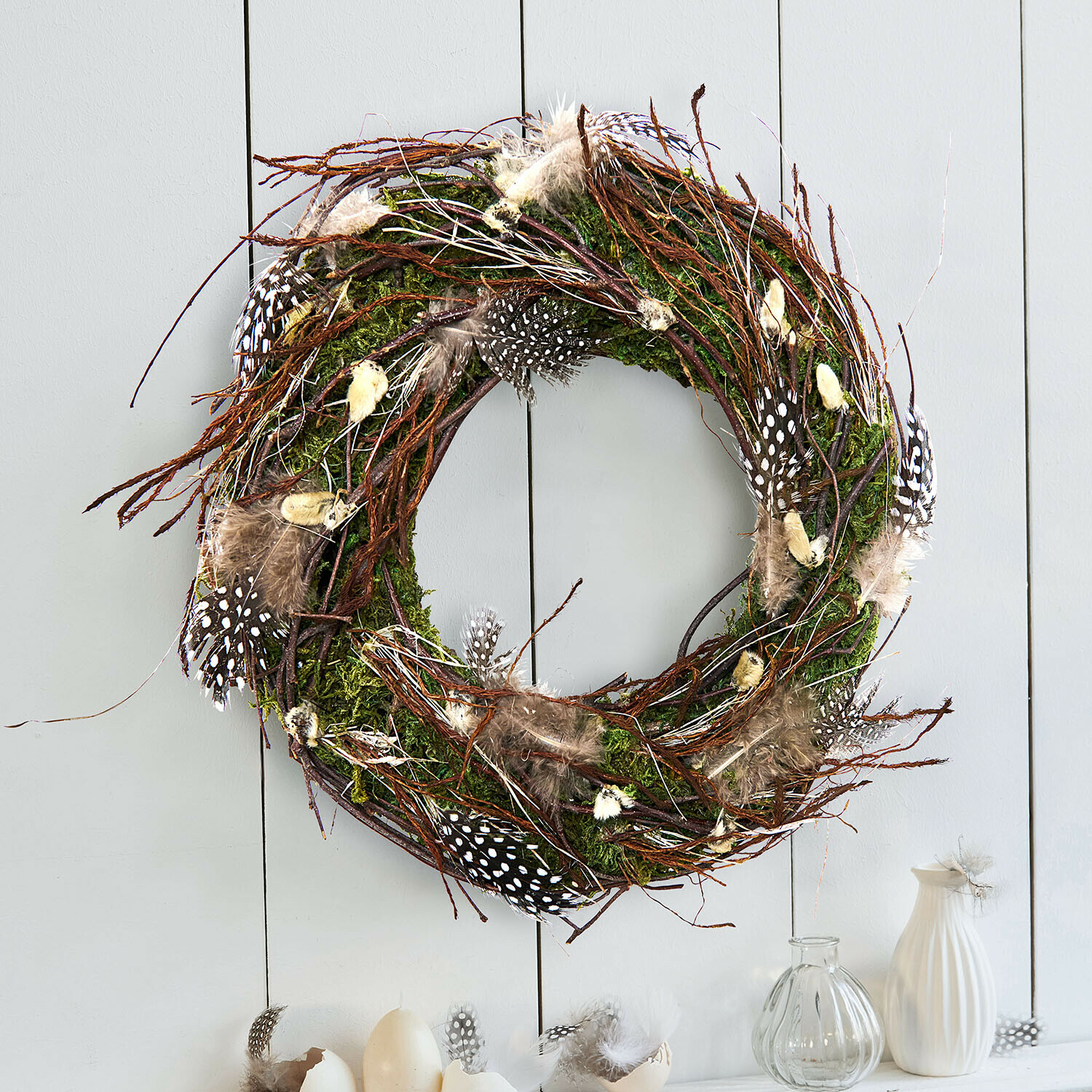 Dekorativer Kranz aus Zweigen, Moos und Federn in natürlichen Farben für Wanddeko