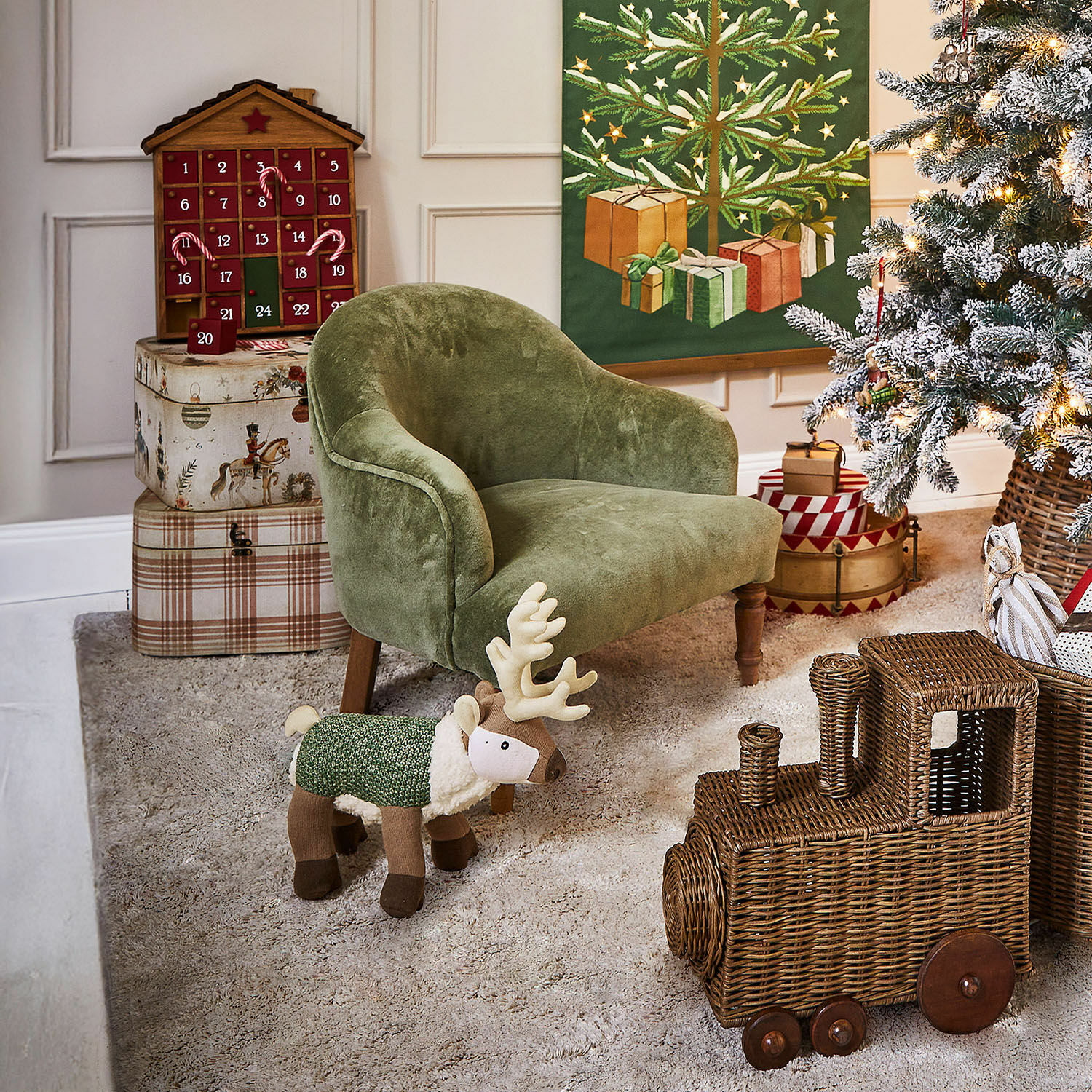 Grüner Kindersessel mit Plüsch-Rentier und geflochtenem Zugspielzeug in weihnachtlich dekoriertem Raum