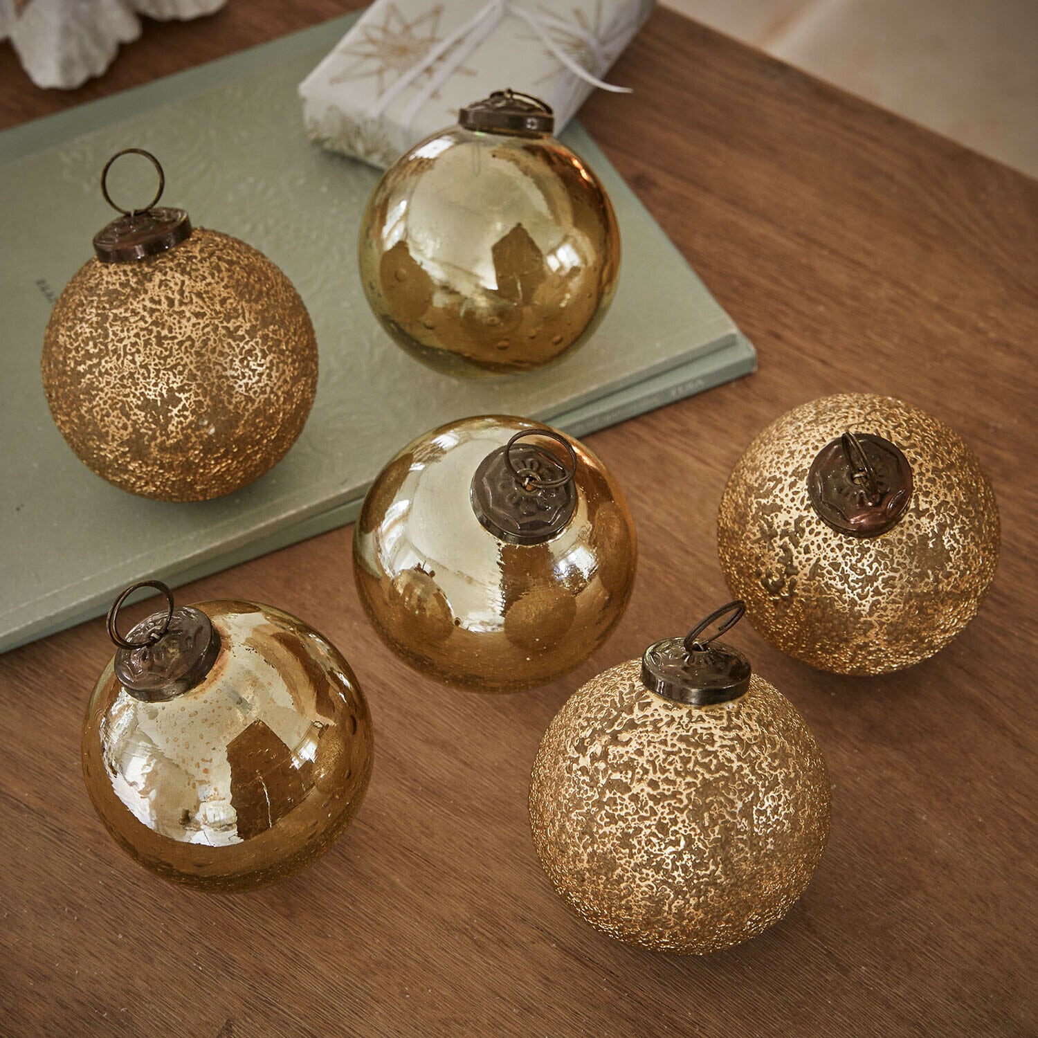 Weihnachtskugel 6er Set Fioravino Set aus sechs goldfarbenen Weihnachtskugeln aus Glas mit verschiedenen Oberflächen auf Holztisch