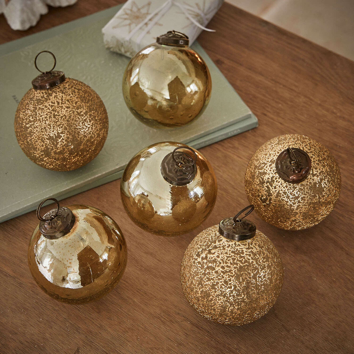 Set aus sechs goldfarbenen Weihnachtskugeln aus Glas mit verschiedenen Oberflächen auf Holztisch