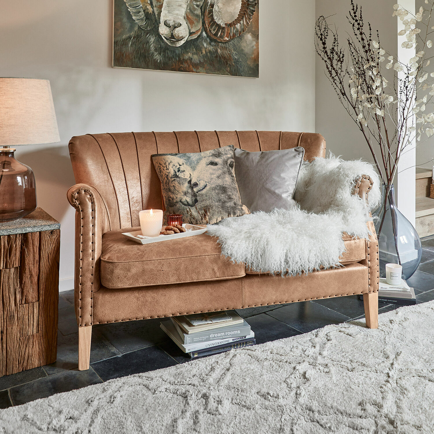 Sofa Brookfield Braunes Sofa aus weichem Material mit dekorativen Kissen und weißem Fellplaid im Wohnzimmer