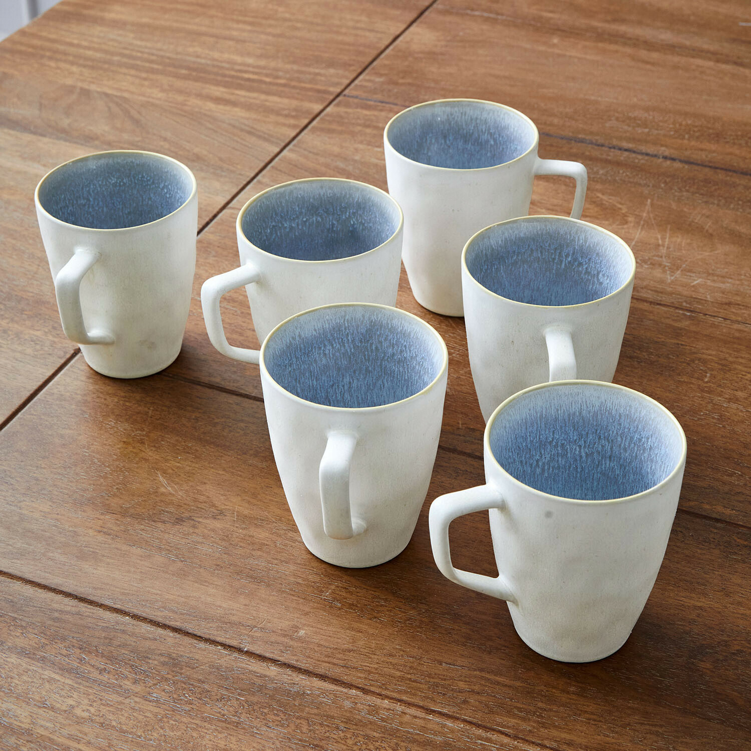 Tasse 6er Set Vionette Sechsteiliges Set cremefarbener Keramiktassen mit blauem Innenraum auf Holztisch