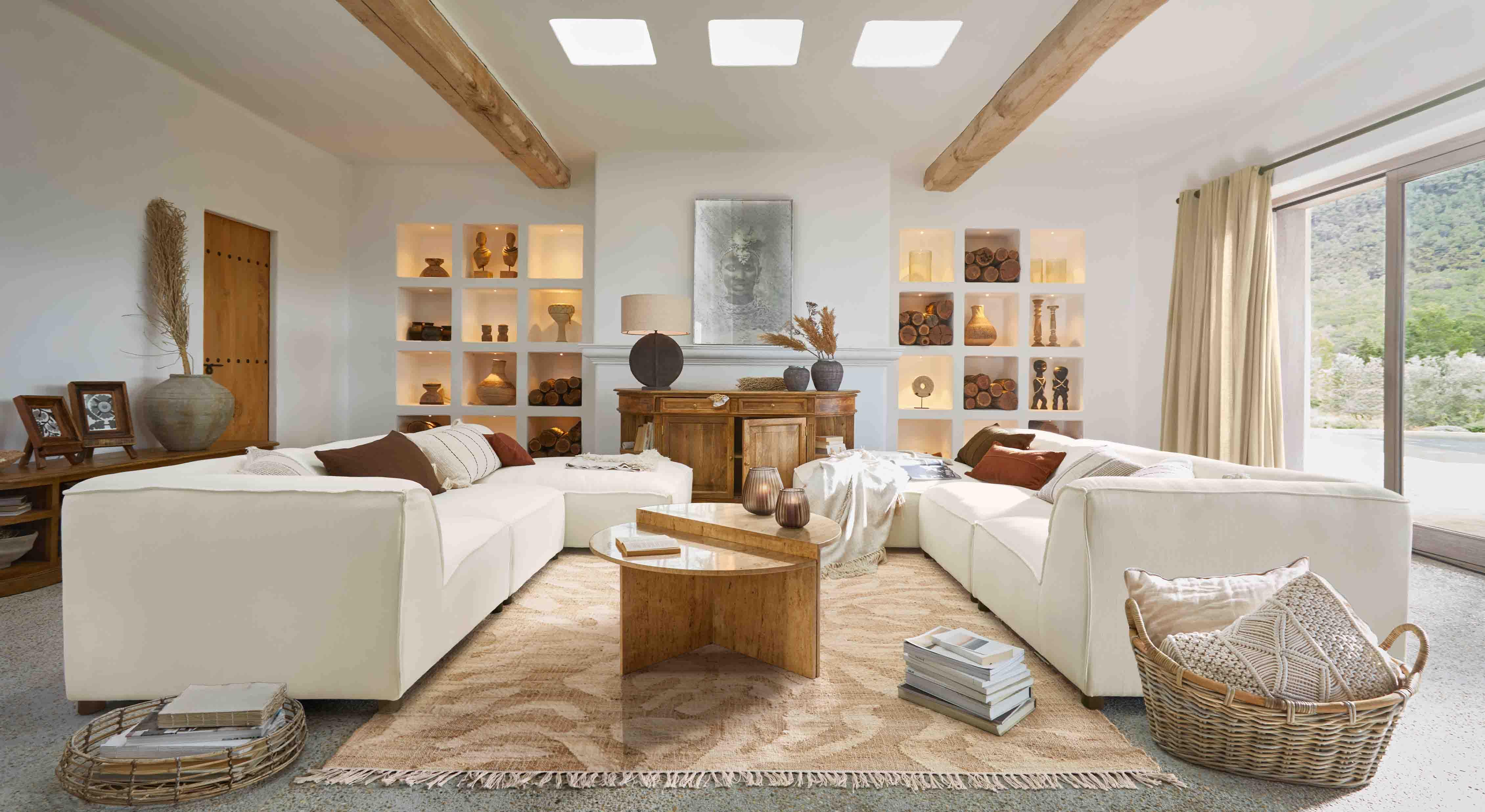 Großzügiges Wohnzimmer mit weißem Ecksofa, Holztisch und warmen Naturdekorationen