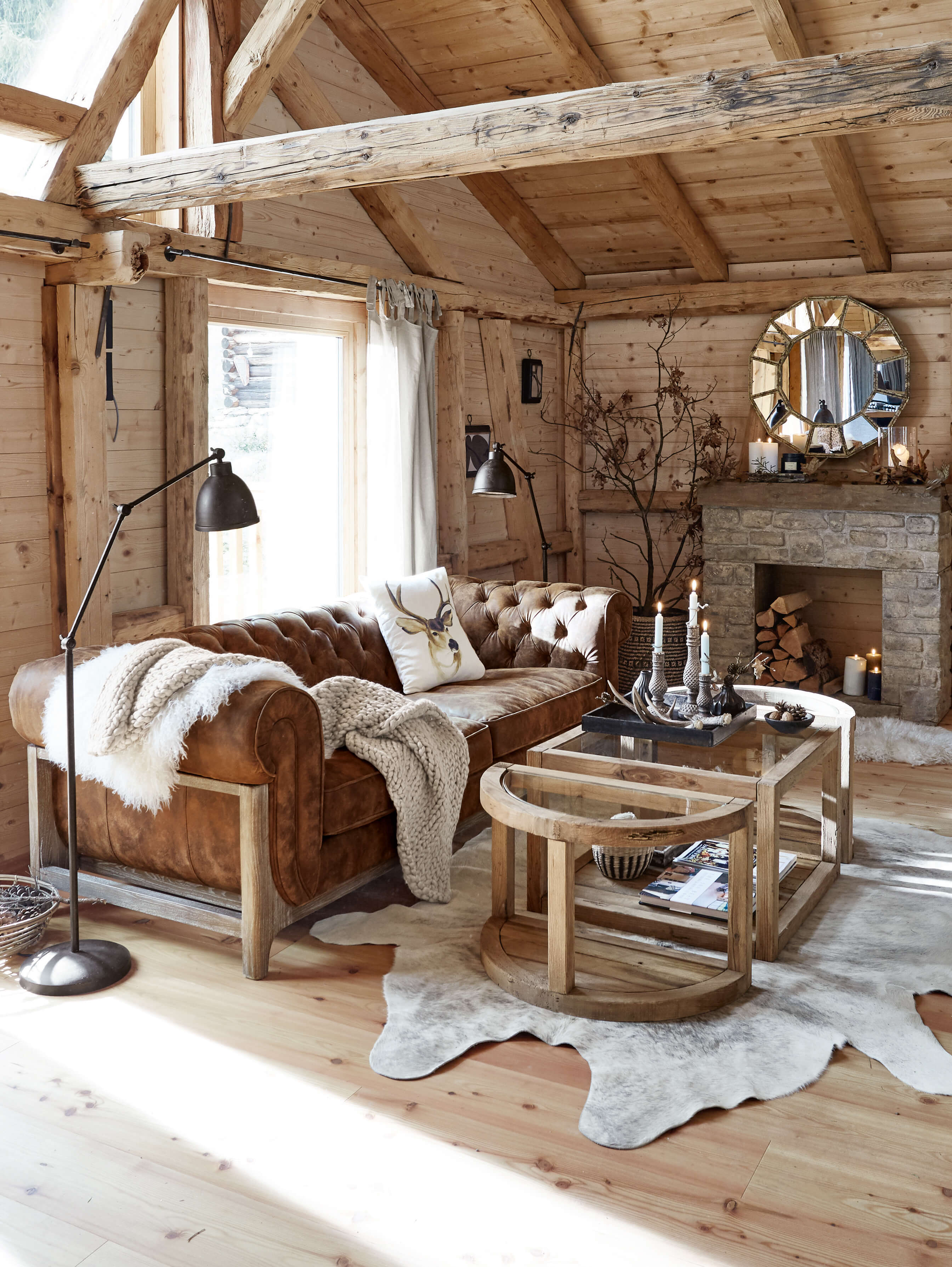 Gemütliches Wohnzimmer mit braunem Ledersofa und Holzcouchtisch auf hellem Holzboden mit Fellteppich