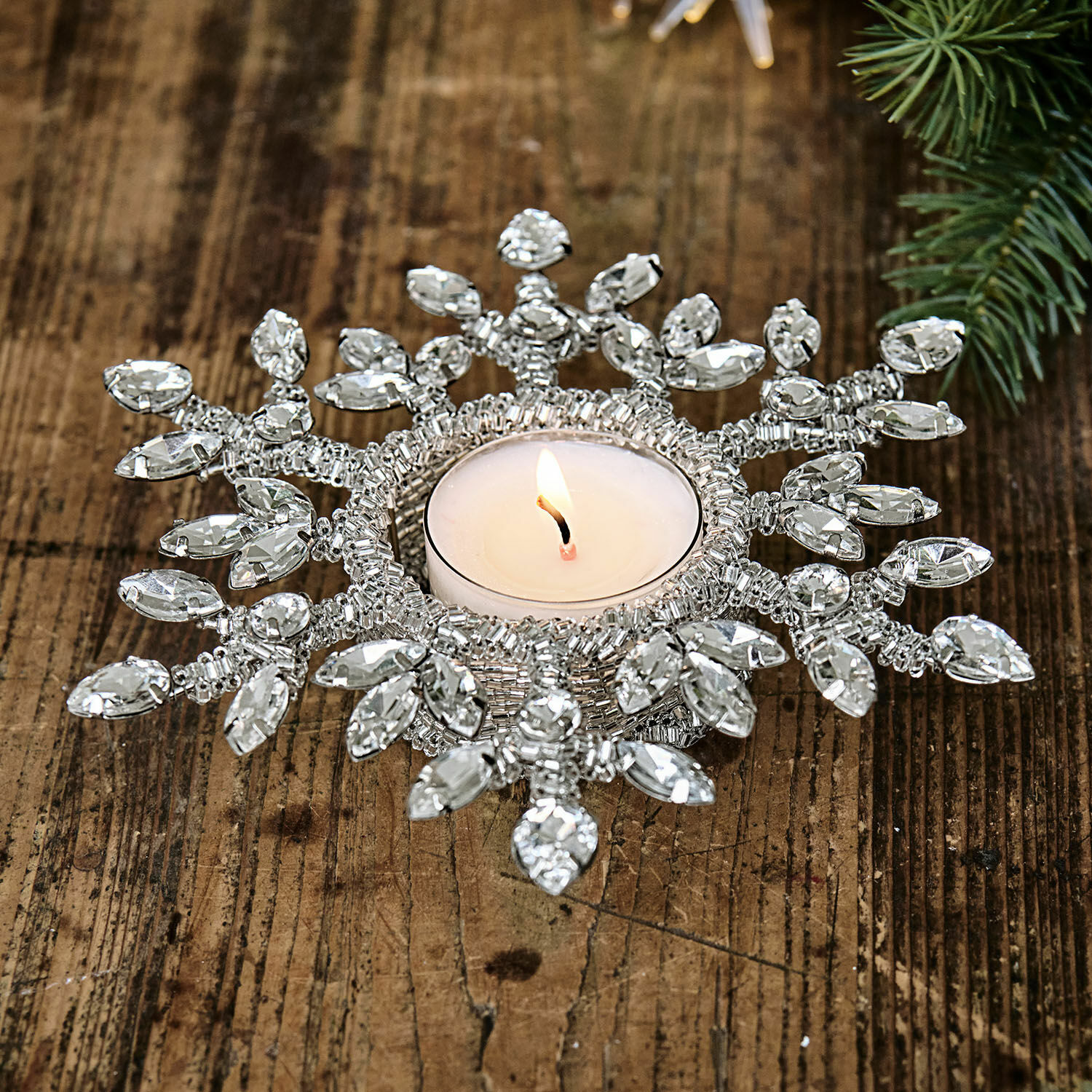Kerzenhalter in Schneeflockenform mit transparenten Kristallen auf Holztisch, Weihnachtsdeko