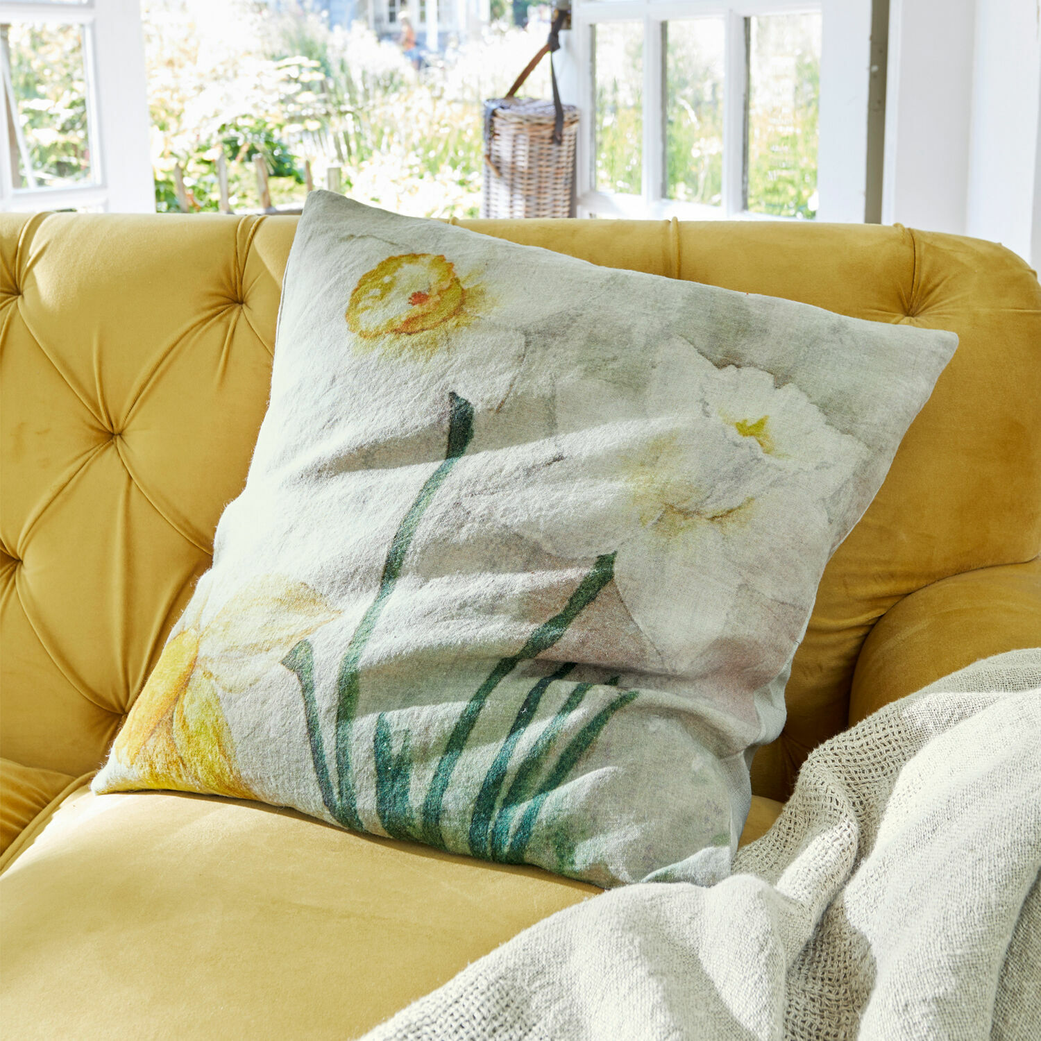 Kissenhülle Misapina Dekoratives Leinenkissen mit pastellfarbenem Blumenmuster auf gelbem Sofa