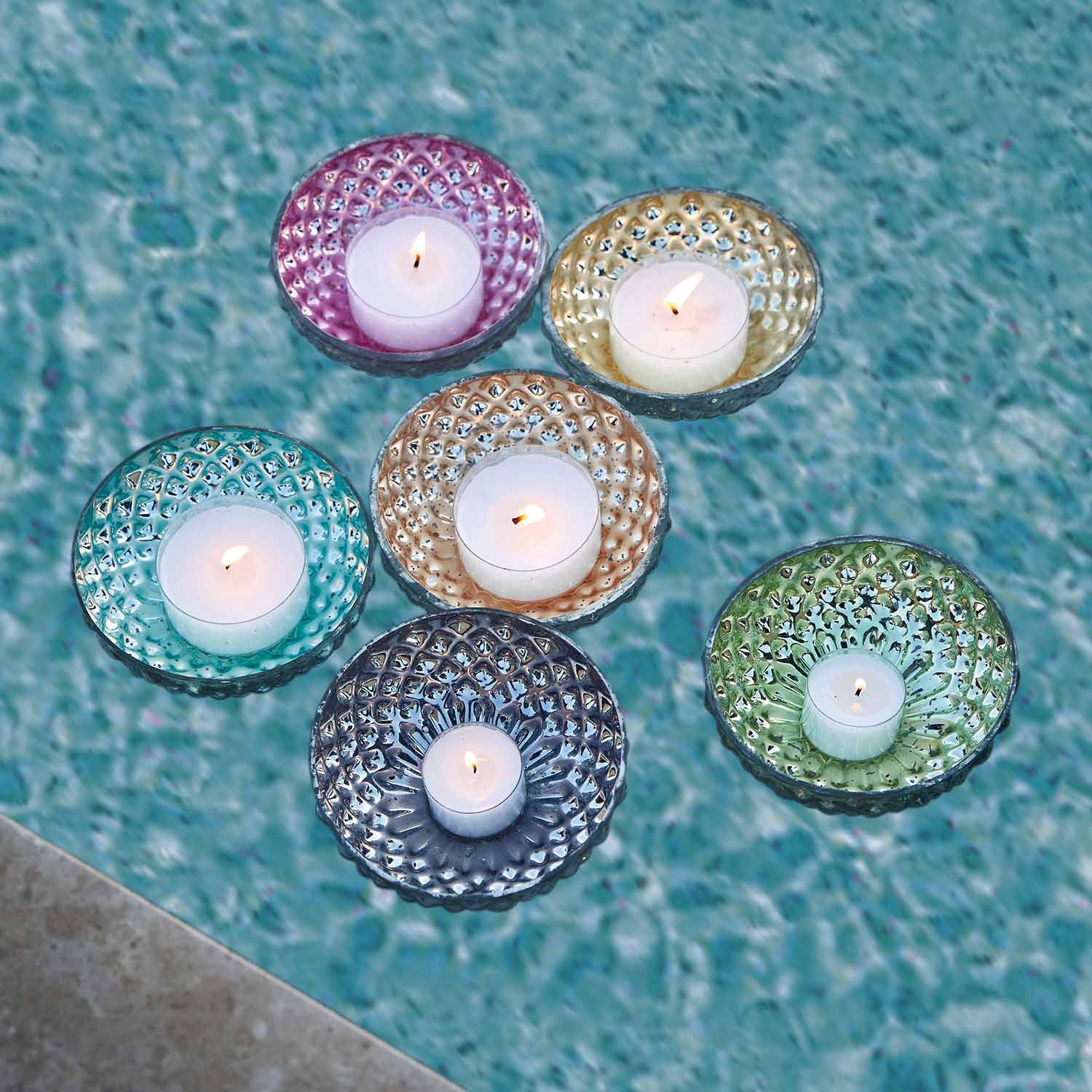 Bunte Glas-Teelichthalter mit weißen schwimmenden Kerzen auf Wasser, Outdoor-Dekoration