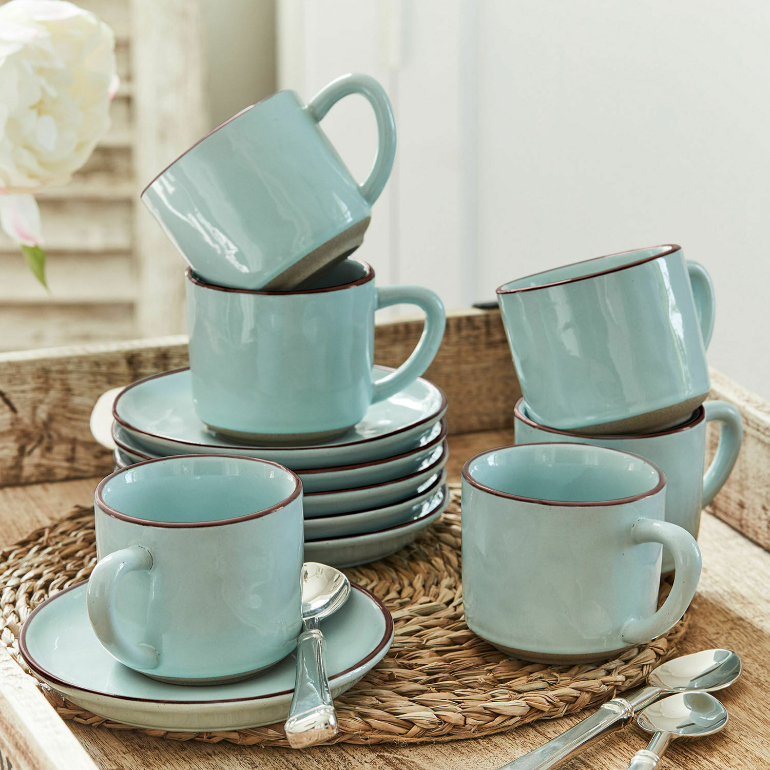 Tasse mit Untertasse 6er Set Biarré Set aus hellblauen Keramiktassen mit Untertassen und Löffeln auf geflochtenem Untersetzer