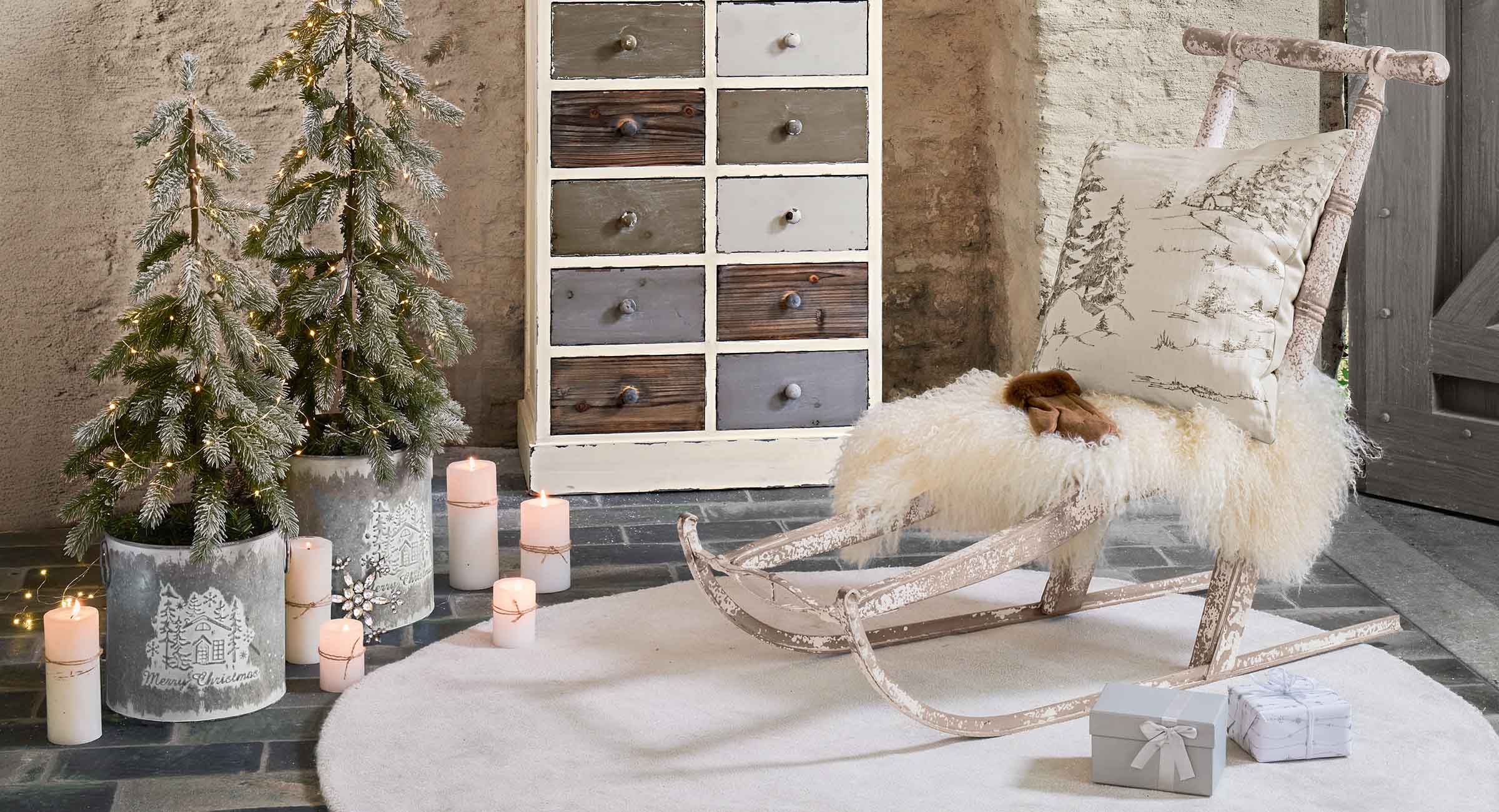 Rustikaler Holzschlitten mit weißem Fell und Kissen mit Wintermotiv in gemütlichem Raum