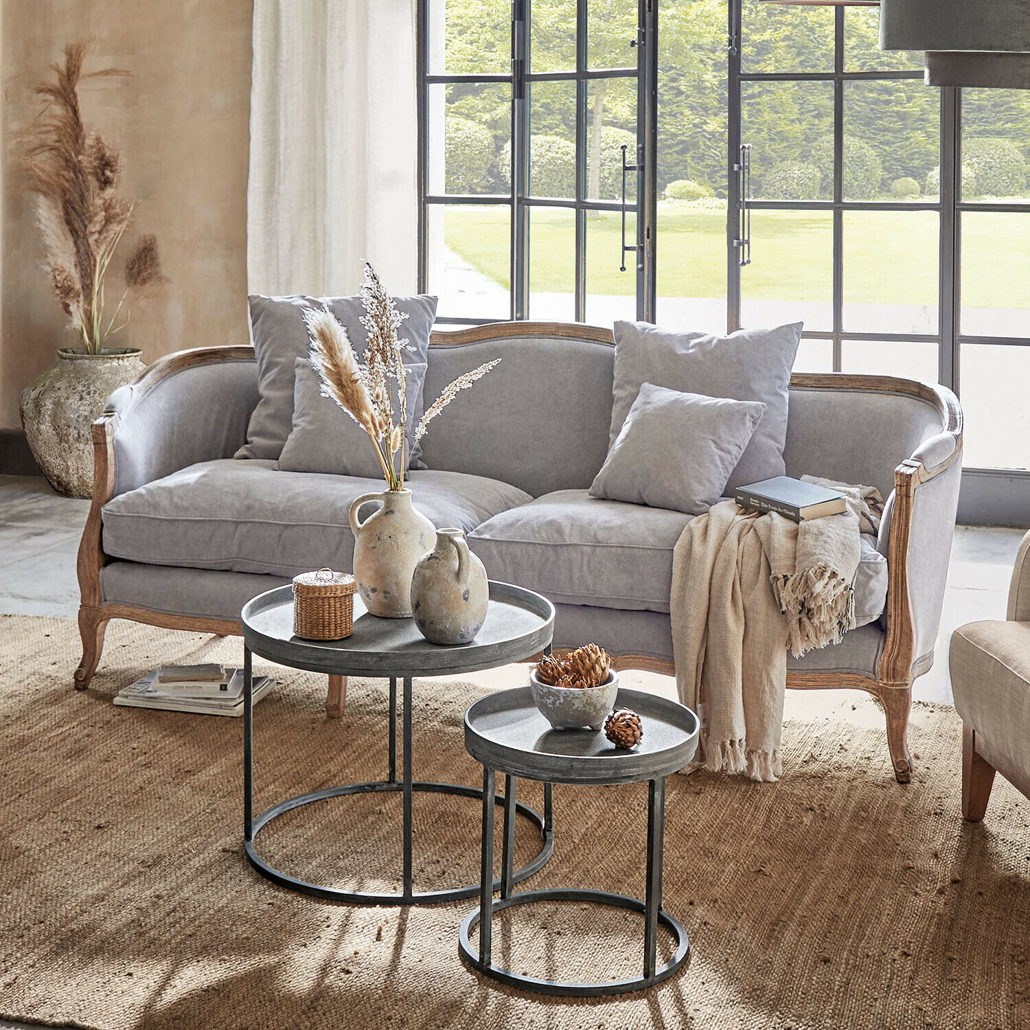 Graues Sofa mit Holzrahmen und Kissen in hellem Wohnzimmer mit Metall-Couchtischen