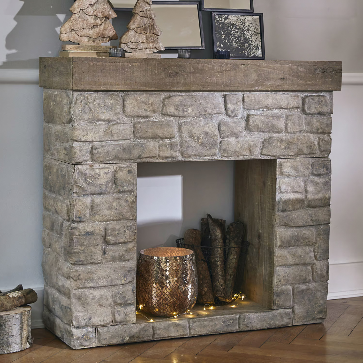 Dekorativer Kamin aus grauem Stein und Holz mit Korb und LED-Lichterkette im Innenraum