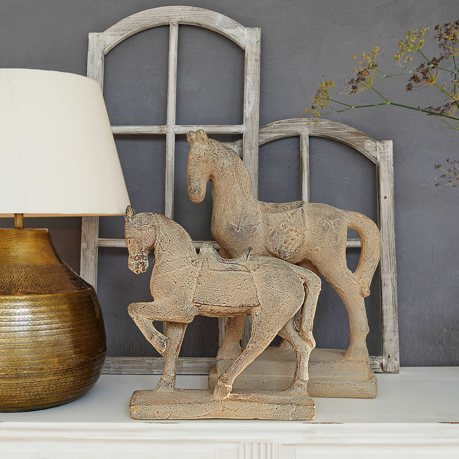 Deko-Pferd 2er Set Mirandel Dekorative Pferdefiguren aus beigem Stein auf weißem Regal mit Lampe und Holzfensterrahmen