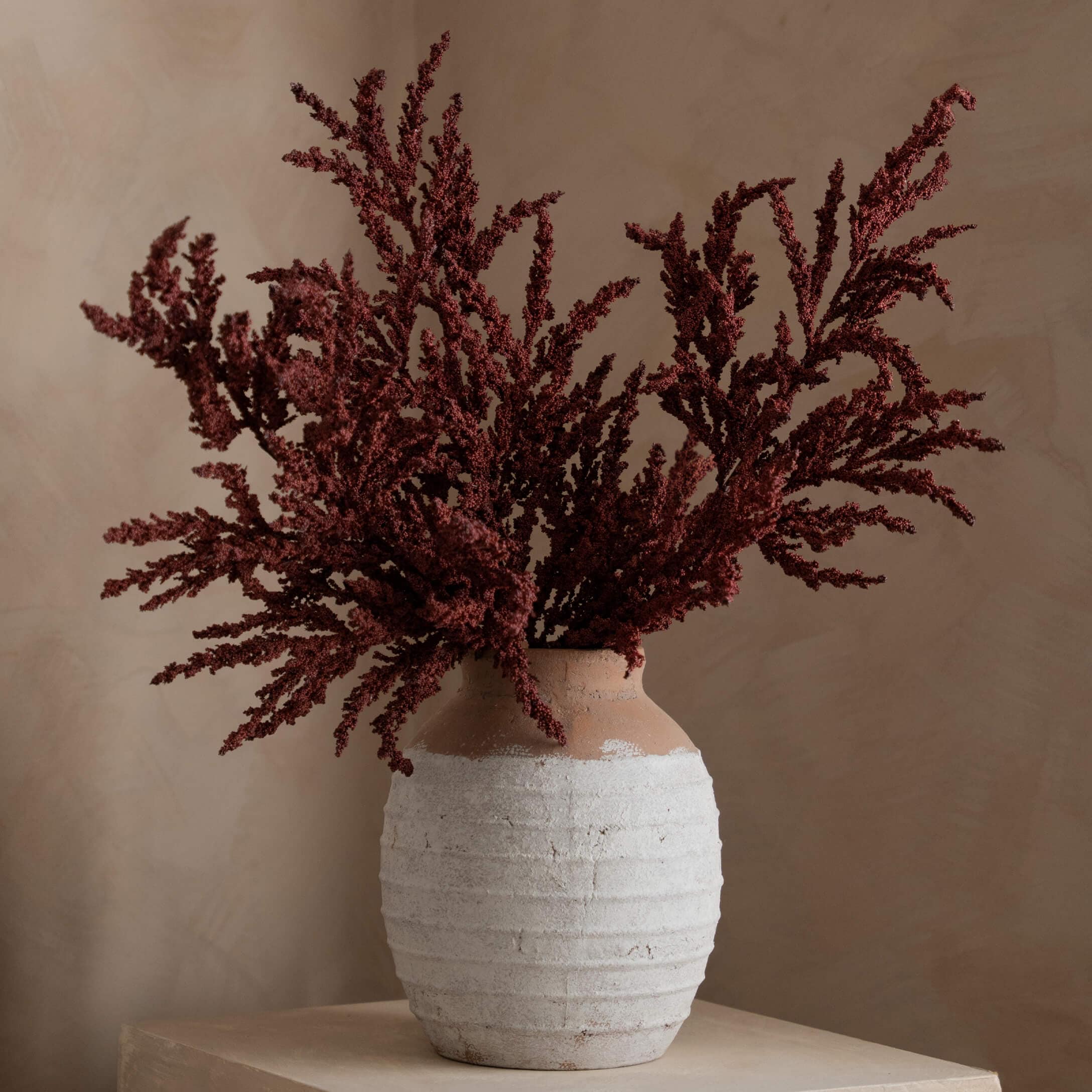 Keramikvase in Weiß und Braun mit getrockneten roten Blumen als Wohnaccessoire