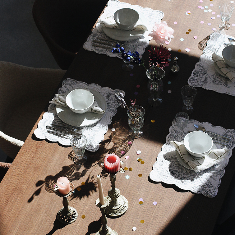 Eleganter gedeckter Tisch mit weißen Tellern, Gläsern und Kerzen auf Holzplatte