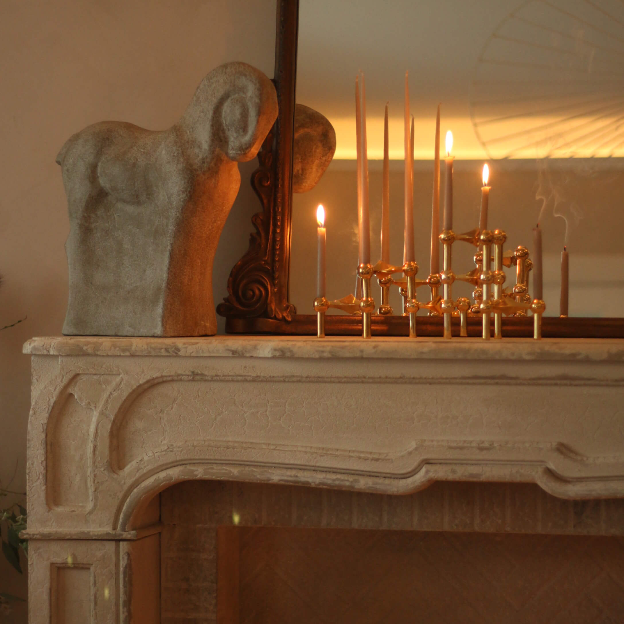 Dekorative Steinskulptur eines Widders auf Kamin mit Messingkerzenhalter und brennenden Kerzen