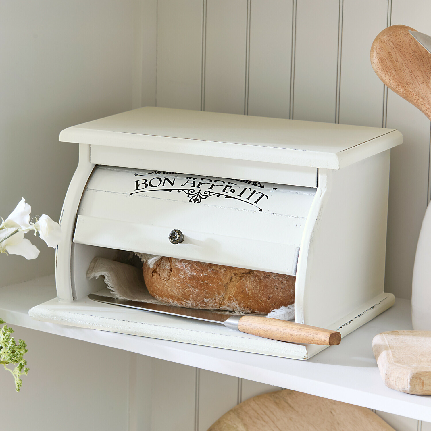 Weißer Brotkasten aus Holz mit Aufschrift Bon Appétit und Brotmesser auf Küchenregal