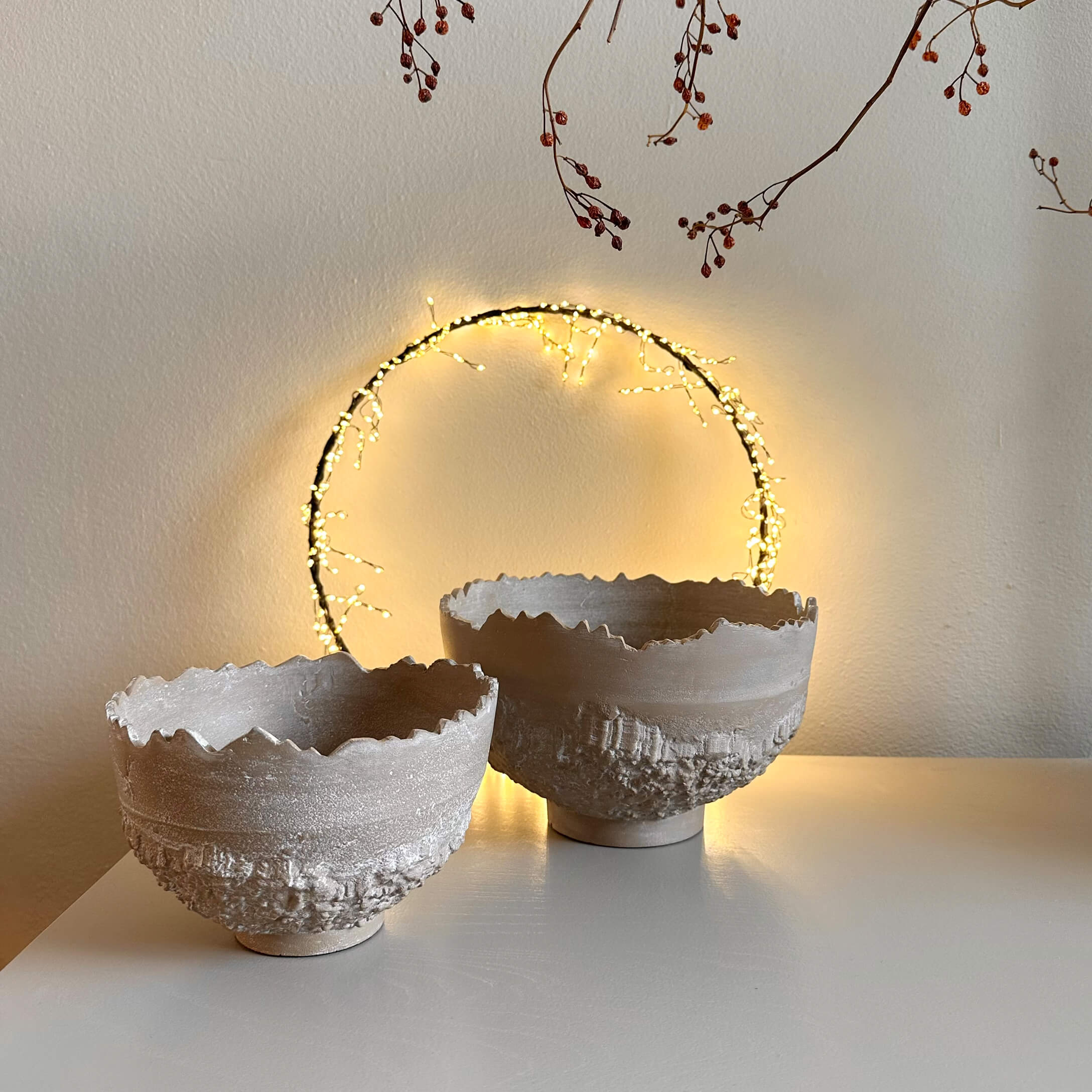 Zwei dekorative beige Keramikschalen mit rauer Struktur und unregelmäßigem Rand auf weißem Tisch