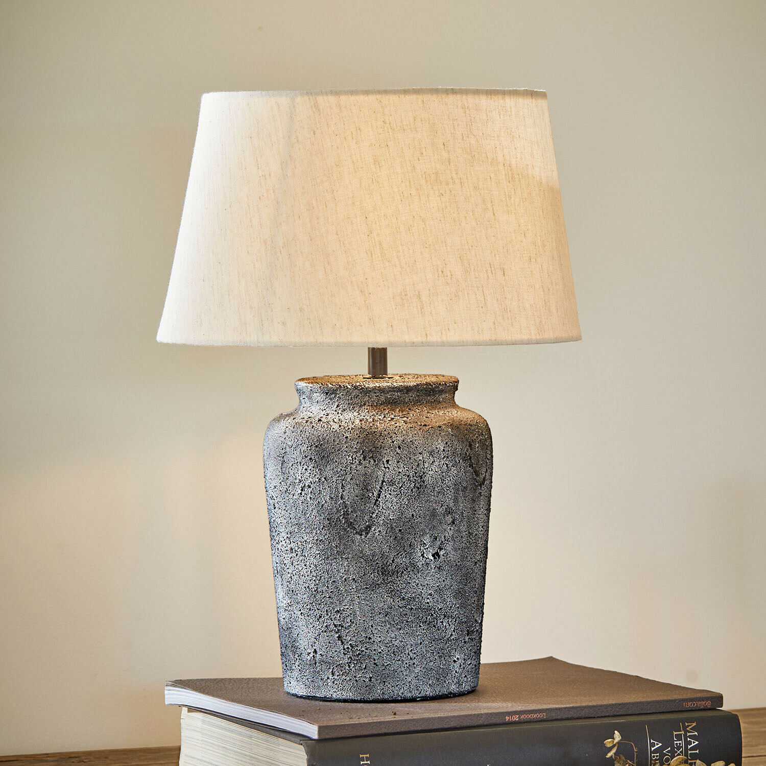 Tischlampe Karvienne Tischlampe mit grauer Keramikbasis und cremefarbenem Lampenschirm auf Büchern, Wohnaccessoire