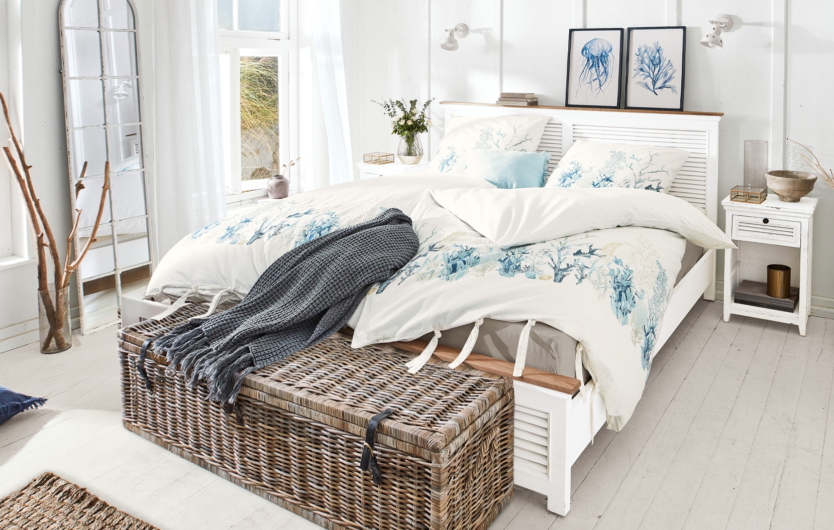 Maritimes Schlafzimmer mit weißem Bett und Bettwäsche mit blauem Meerespflanzen- und Tiermotiv