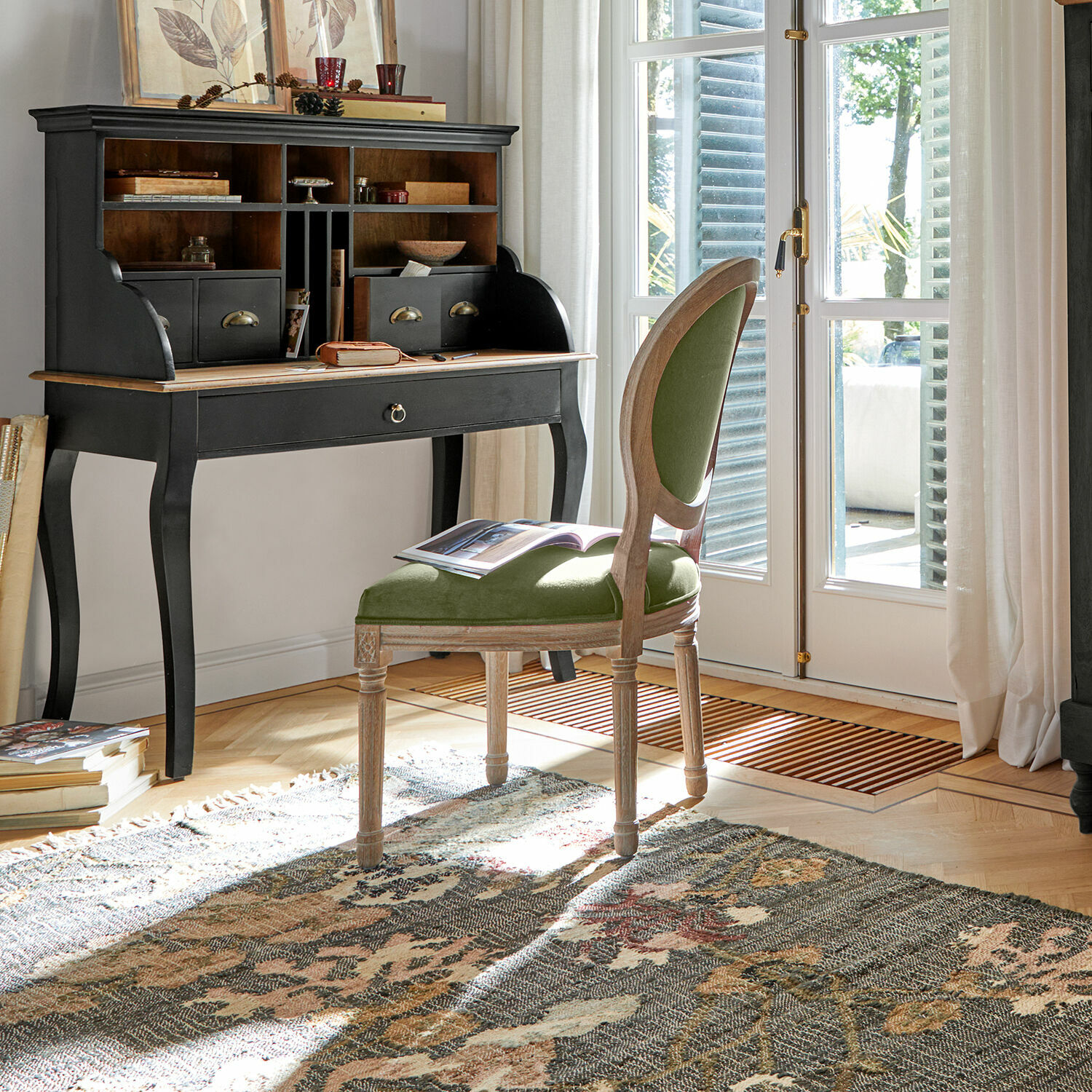 Klassischer schwarzer Holzsekretär mit Fächern und grün gepolstertem Stuhl in hellem Raum