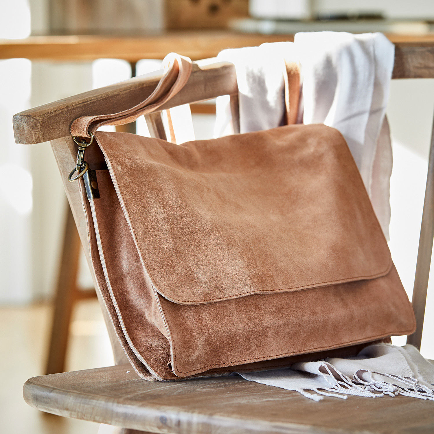 Tasche Chanzelle Braune Umhängetasche aus weichem Veloursleder auf einem Holzstuhl, modisches Accessoire für den Alltag
