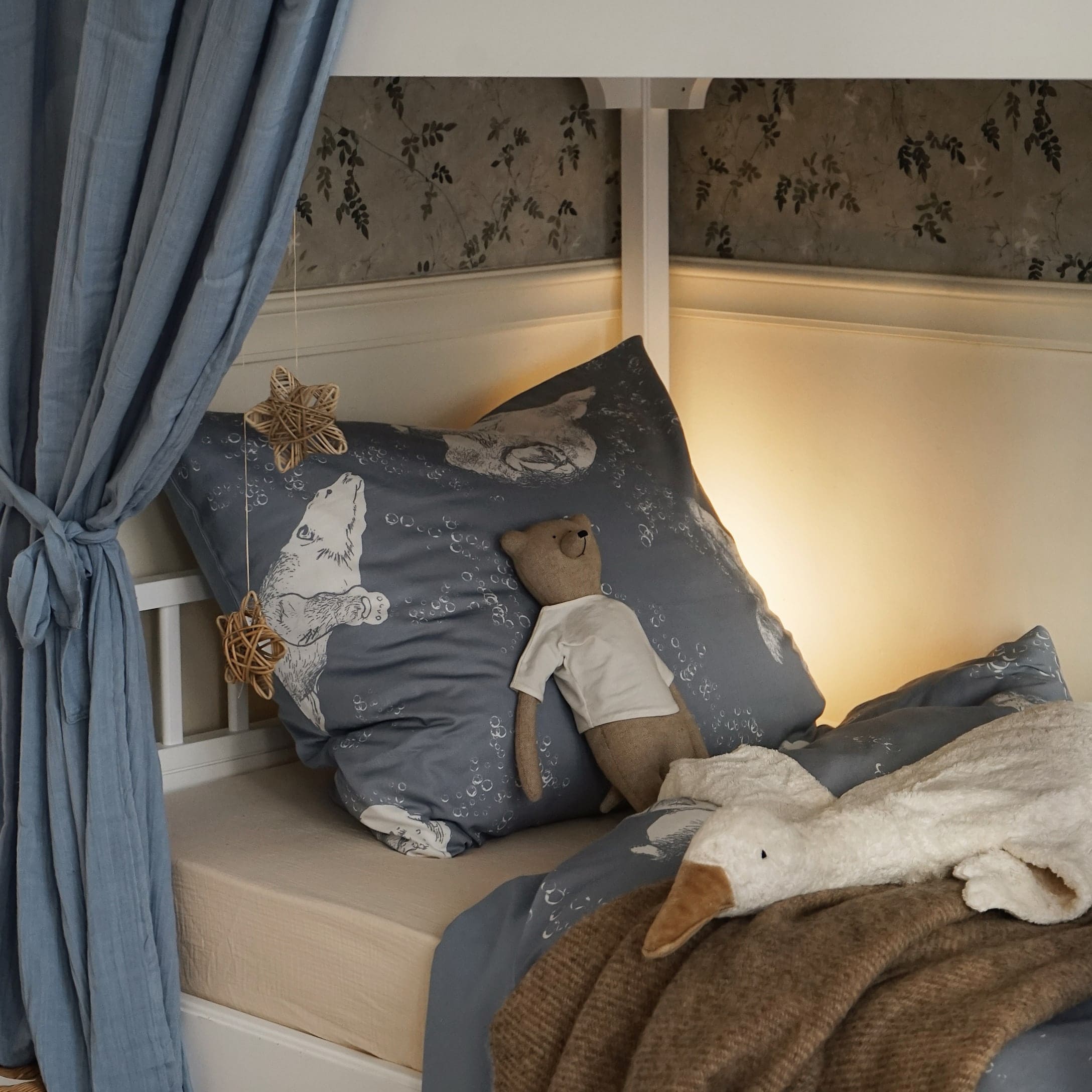 Blaue Bettwäsche mit Bärenmotiv und weiche Plüschtiere auf einem Kinderbett