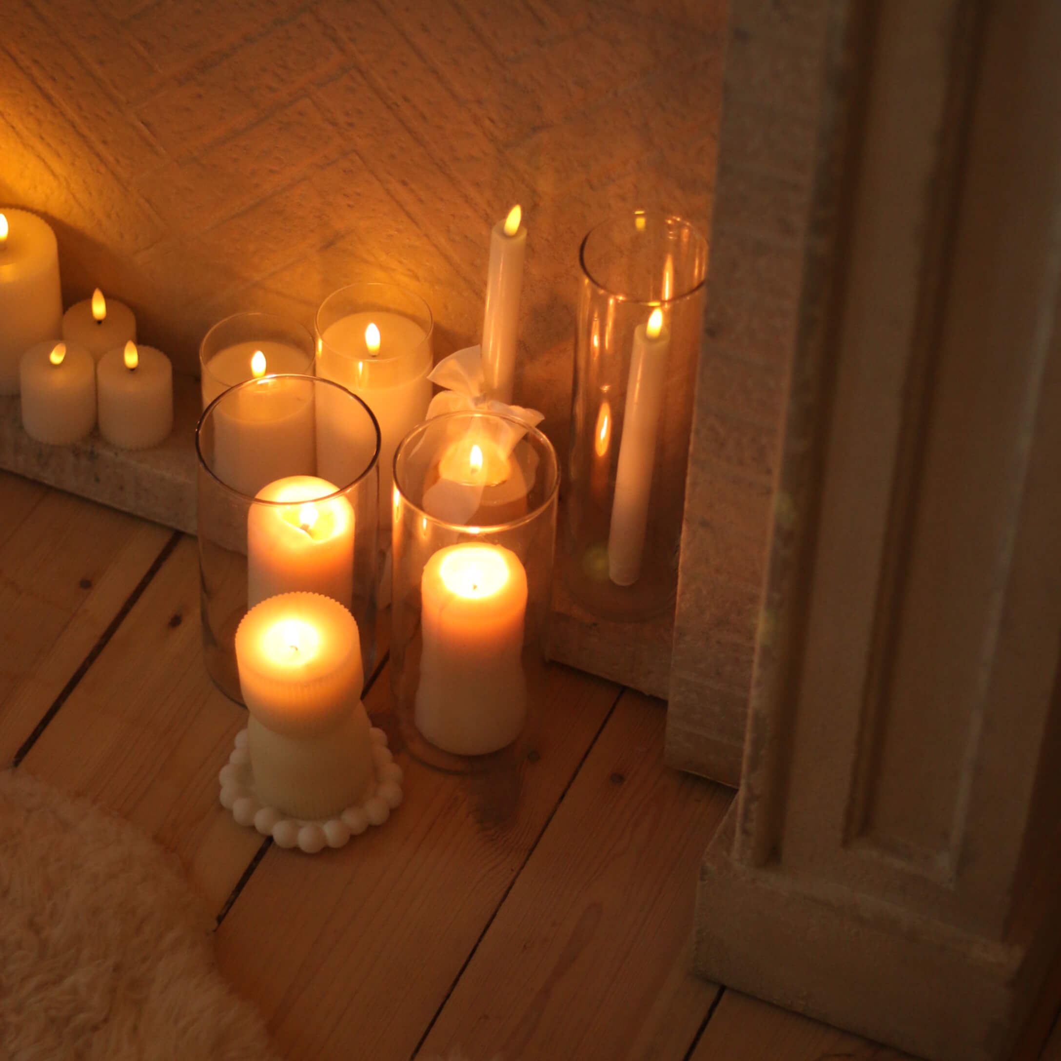 Verschiedene weiße Kerzen in unterschiedlichen Formen und Größen auf Holzboden, Wohnraumdekoration