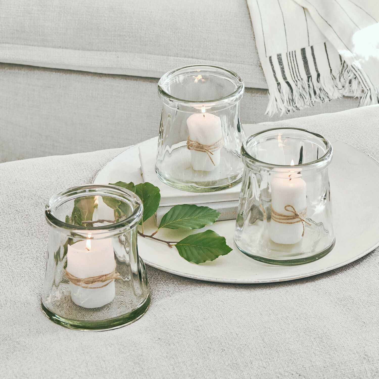 Windlicht 3er Set Gravière Set aus drei Glaswindlichtern mit weißen Kerzen und Naturkordel auf hellem Hintergrund