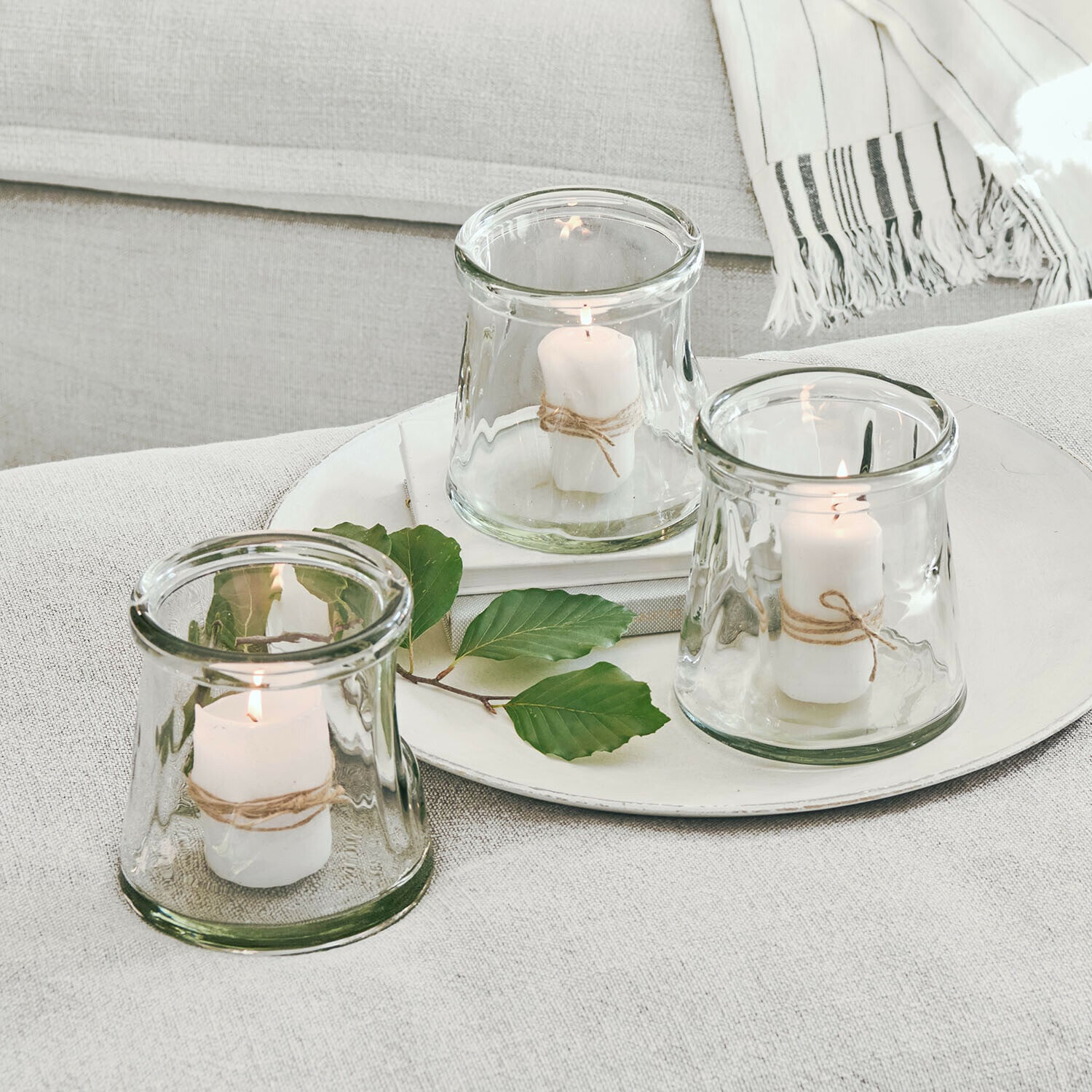 Windlicht 3er Set Gravière Set aus drei Glaswindlichtern mit weißen Kerzen und Naturkordel auf hellem Hintergrund